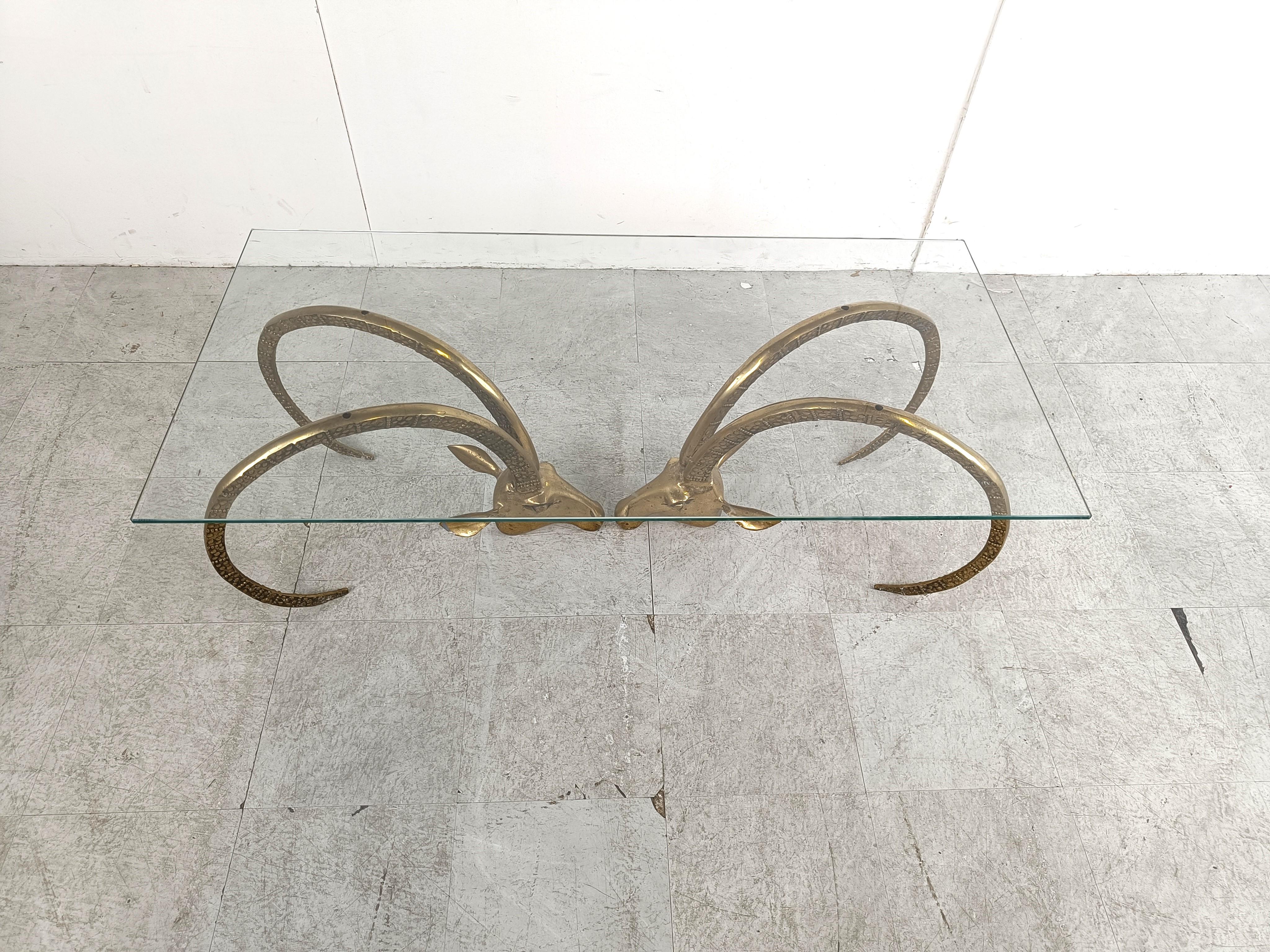 Seventies glam coffee table with a clear glass top supported by two brass ibex or antilopes sculptures.

Elegant shape with the right patina.

Sometimes attributed to Alain Chervet

1970s - France

Dimensions:
Table:
Height: 42cm/16.53