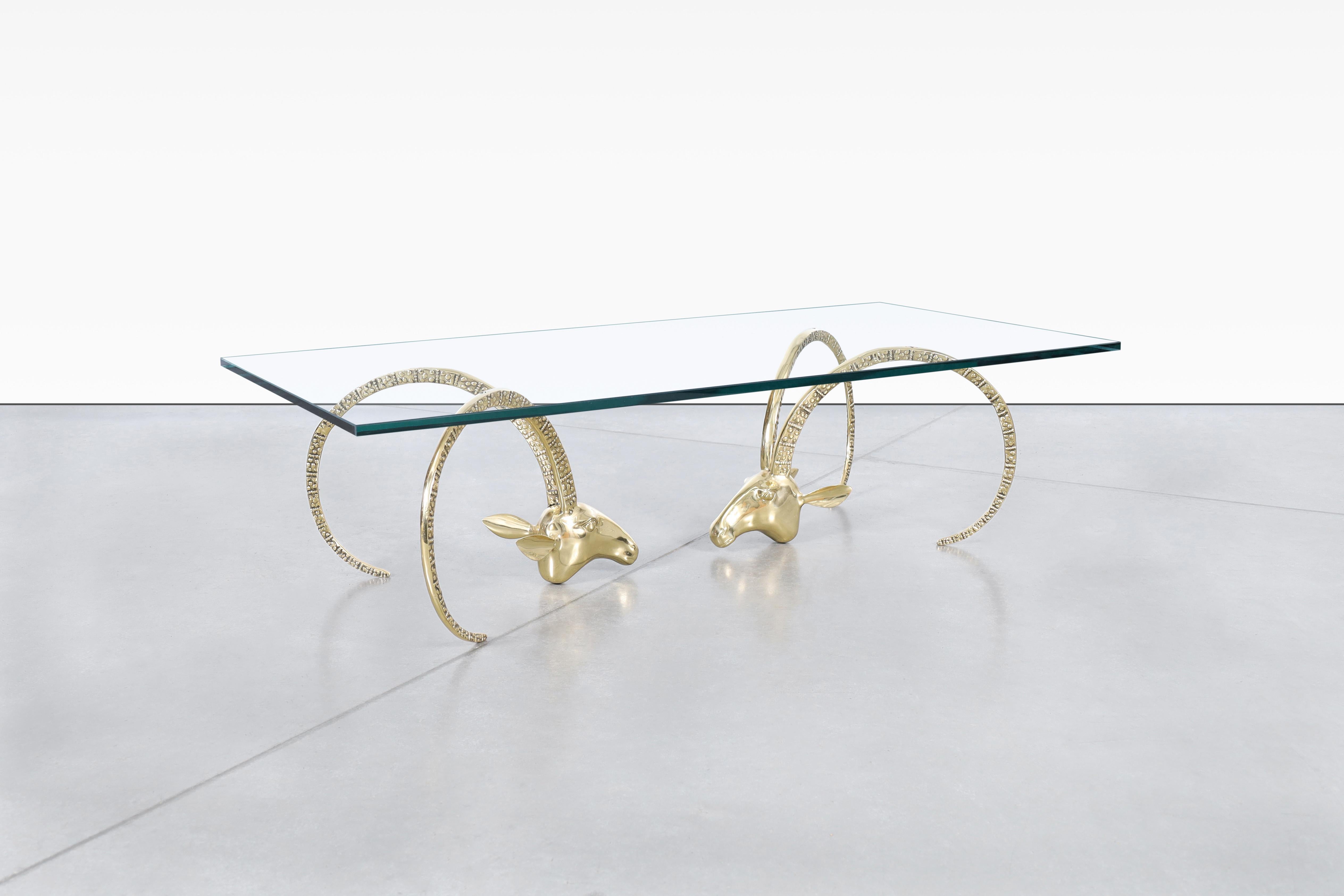 La table basse à tête de bélier en laiton avec plateau en verre est une pièce d'apparat frappante qui apporte une touche d'élégance et d'audace artistique à tout espace de vie. La base de la table présente des têtes de bélier travaillées de manière