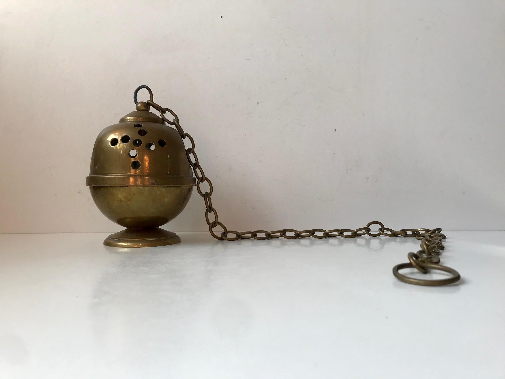 1950s continental incense burner in brass. The plain design testifies that it has been in use. Age consistent ware and patina are present to both the burner and pendulum chain.