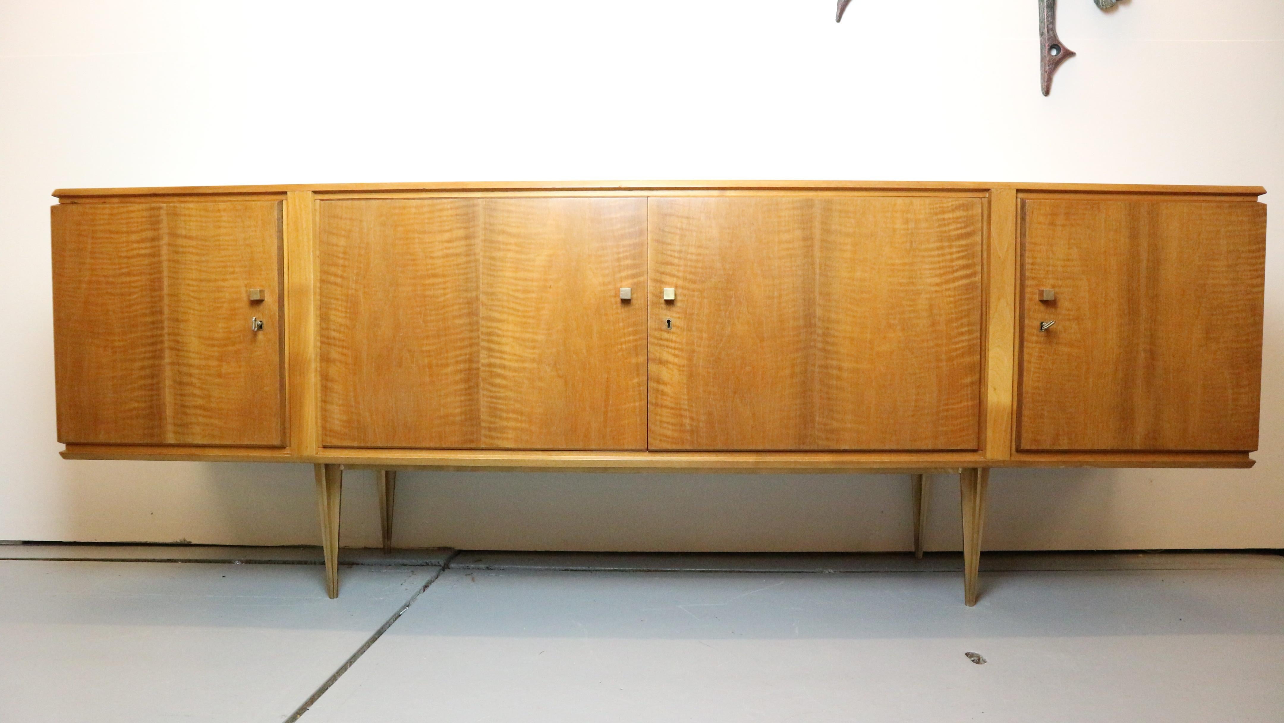 A beautiful and simple light colored walnut sideboard with brass details. 
Including 3 keys to open the doors, behind the doors you find lots of storage room. The brass details and the walnut veneer drawing gives it an very exclusive and modern