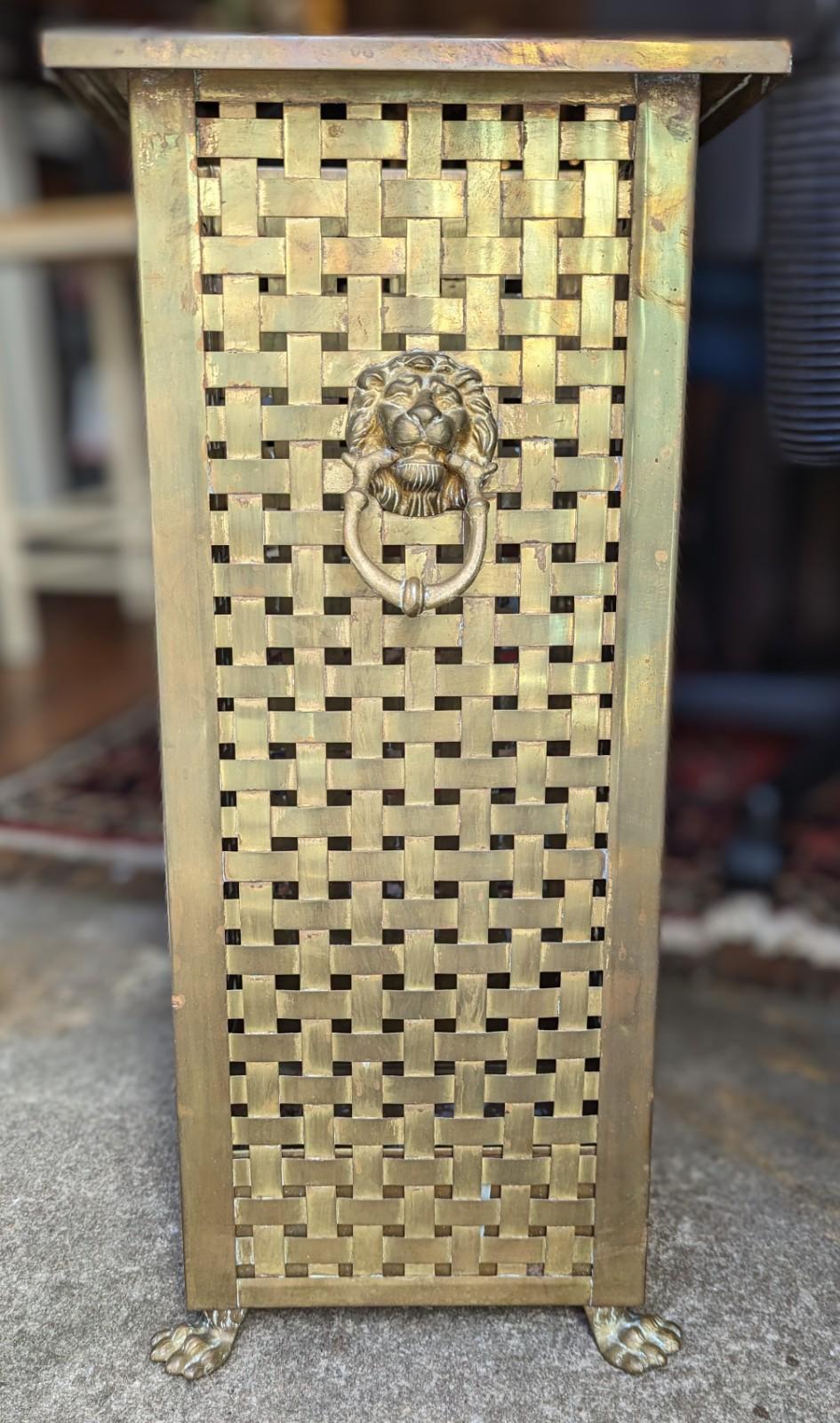 Detailed woven brass umbrella holder stand with doorknocker style lion-head and loop detail on two sides. In the Regency design style, circa early to mid-20th century. In fair well used condition with aged patina to the brass.

Dimensions: 9.75