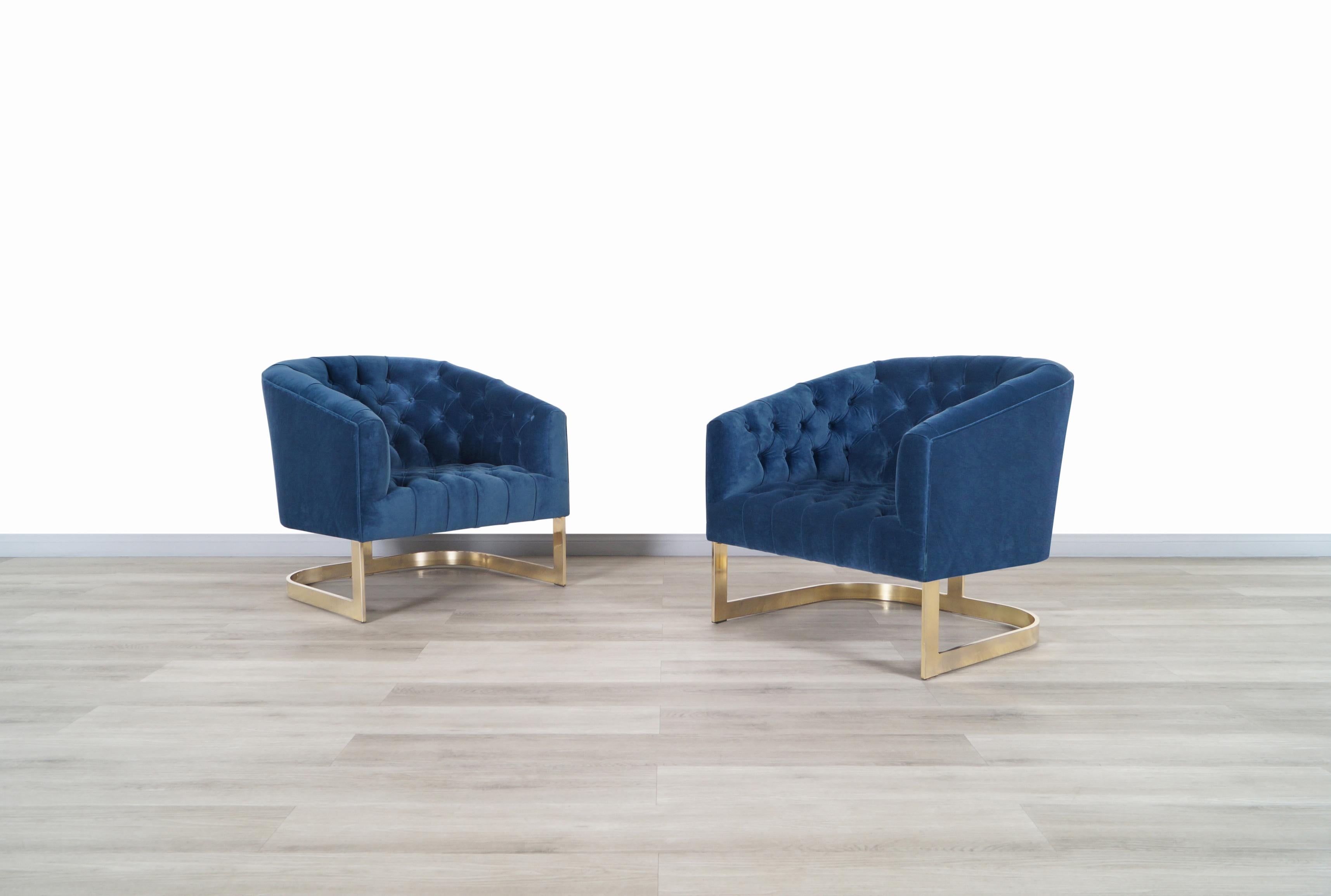 Wonderful vintage brass lounge chairs attributed to Milo Baughman in United States, circa 1970s. Each chair has been professionally reupholstered in a tufted design with soft midnight blue velvet. These chairs stand out for their floating design