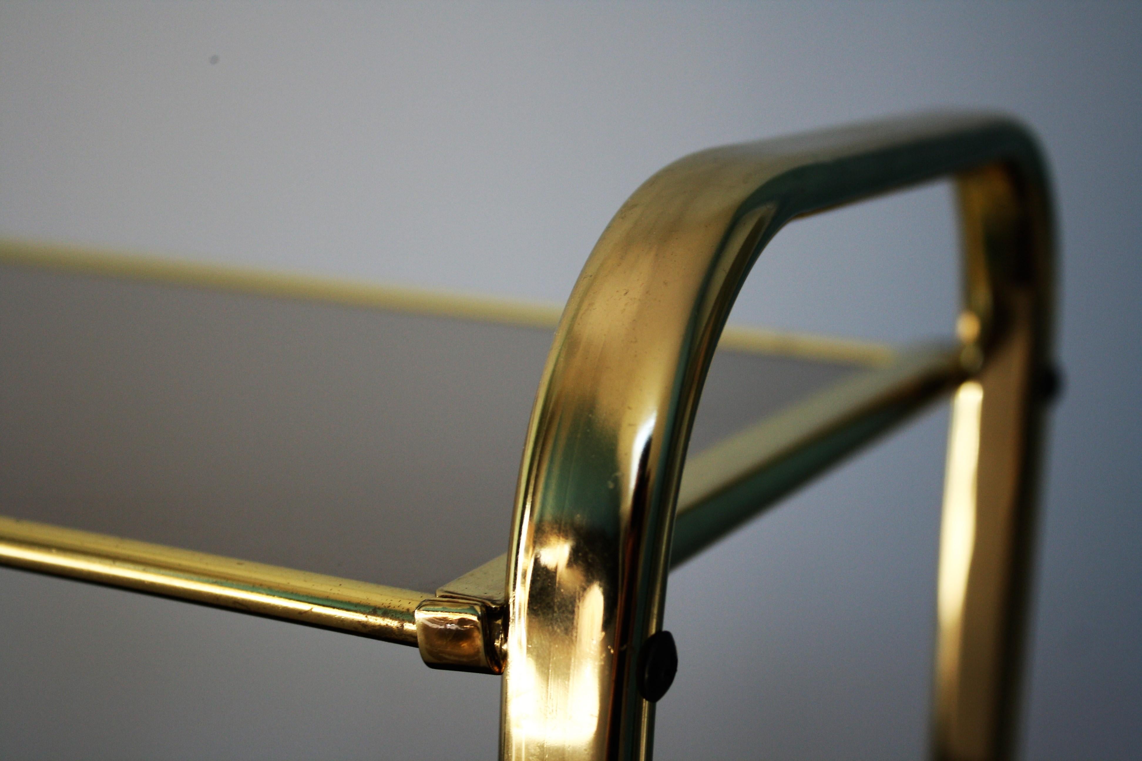 Vintage brass side table with smoked glass top and leatherette or faux leather magazine holder.

The table has wheels and is easily movable.

Very handy table that looks fresh.

Belgium, 1970s.

Measures: Height 50cm/20