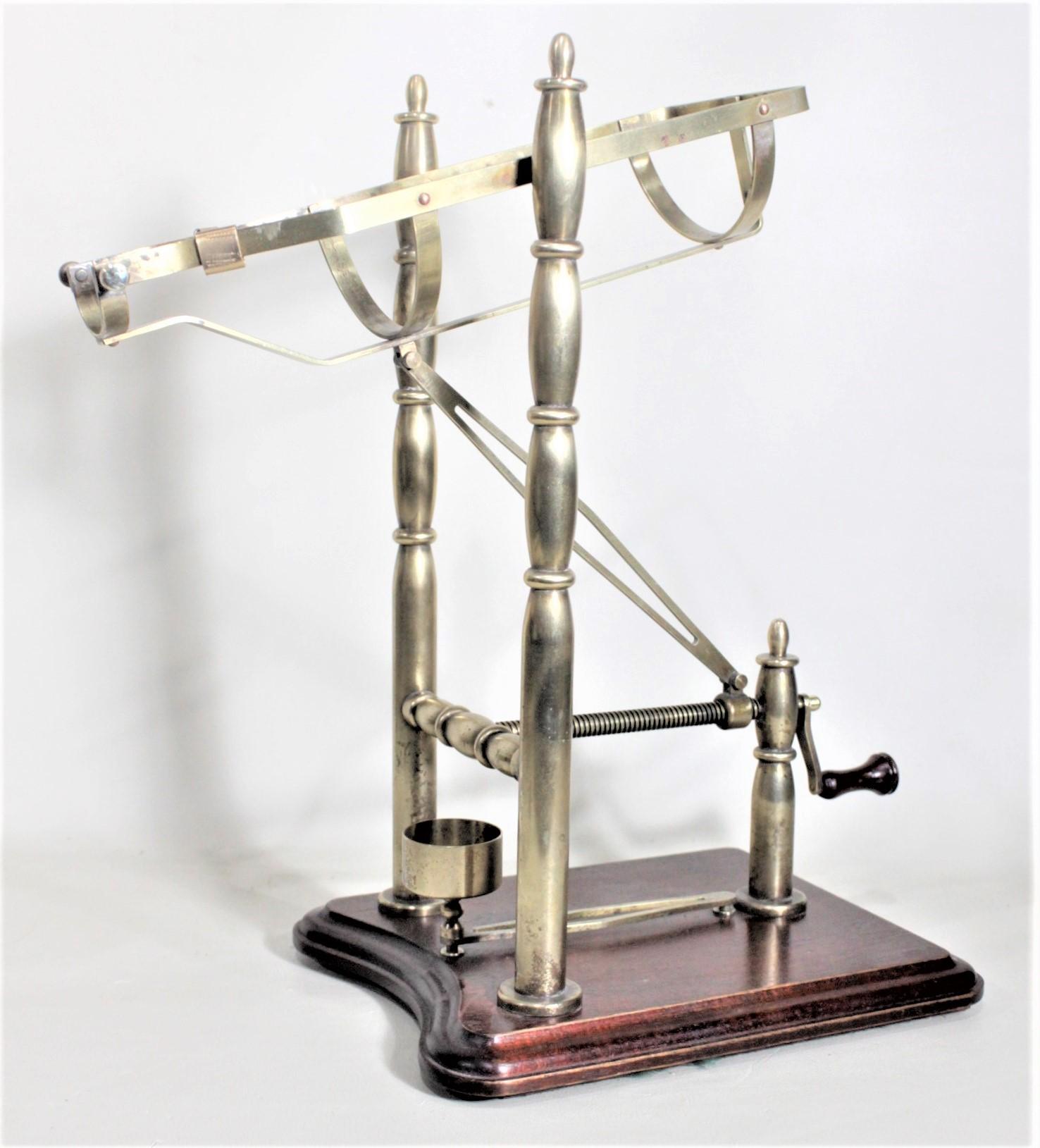 This vintage metal and mahogany port cradle or mechanical wine pourer is unsigned, but presumed to have originated from a European country dating to approximately 1980 and done in a Victorian style. The cradle appears to be composed of a combination