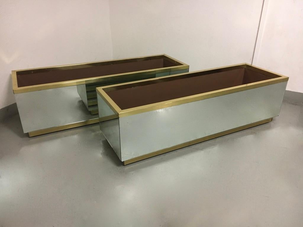 Vintage Mirrored with brass trim and base jardinière or planter, probably Italian ca. 1970s
Few stains on the glass probably due to oxydation but remains a very good looking.
On wheels. Fair vintage condition. 
Price is per item.