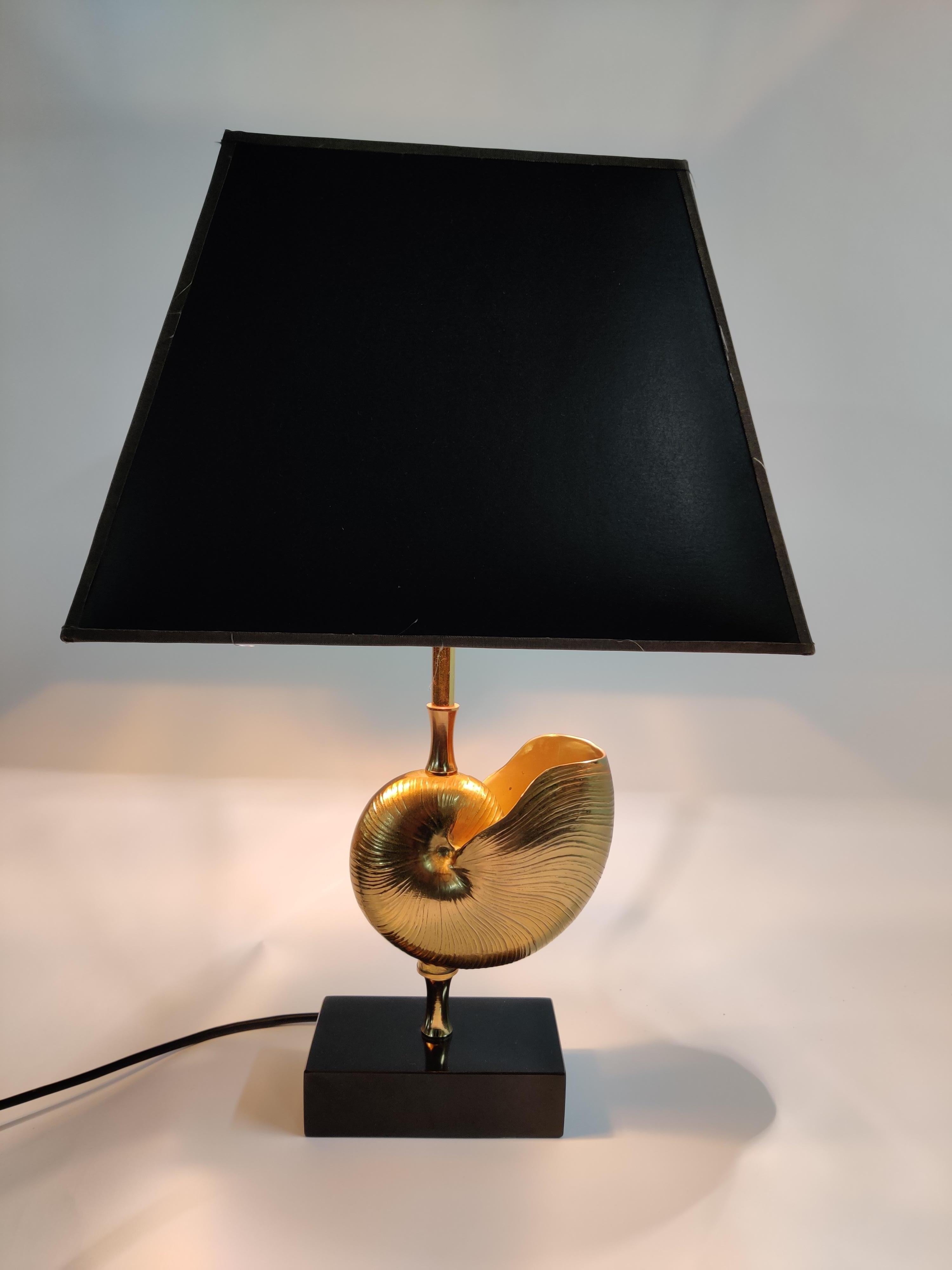 Beautiful brass nautilus shell table lamp in the style of Maison Charles.

This luxurious lamp has a golden nautilus shell center piece.

Good condition.

The lamp works with one standard E27 light bulb and is tested for safe use.

1970s -