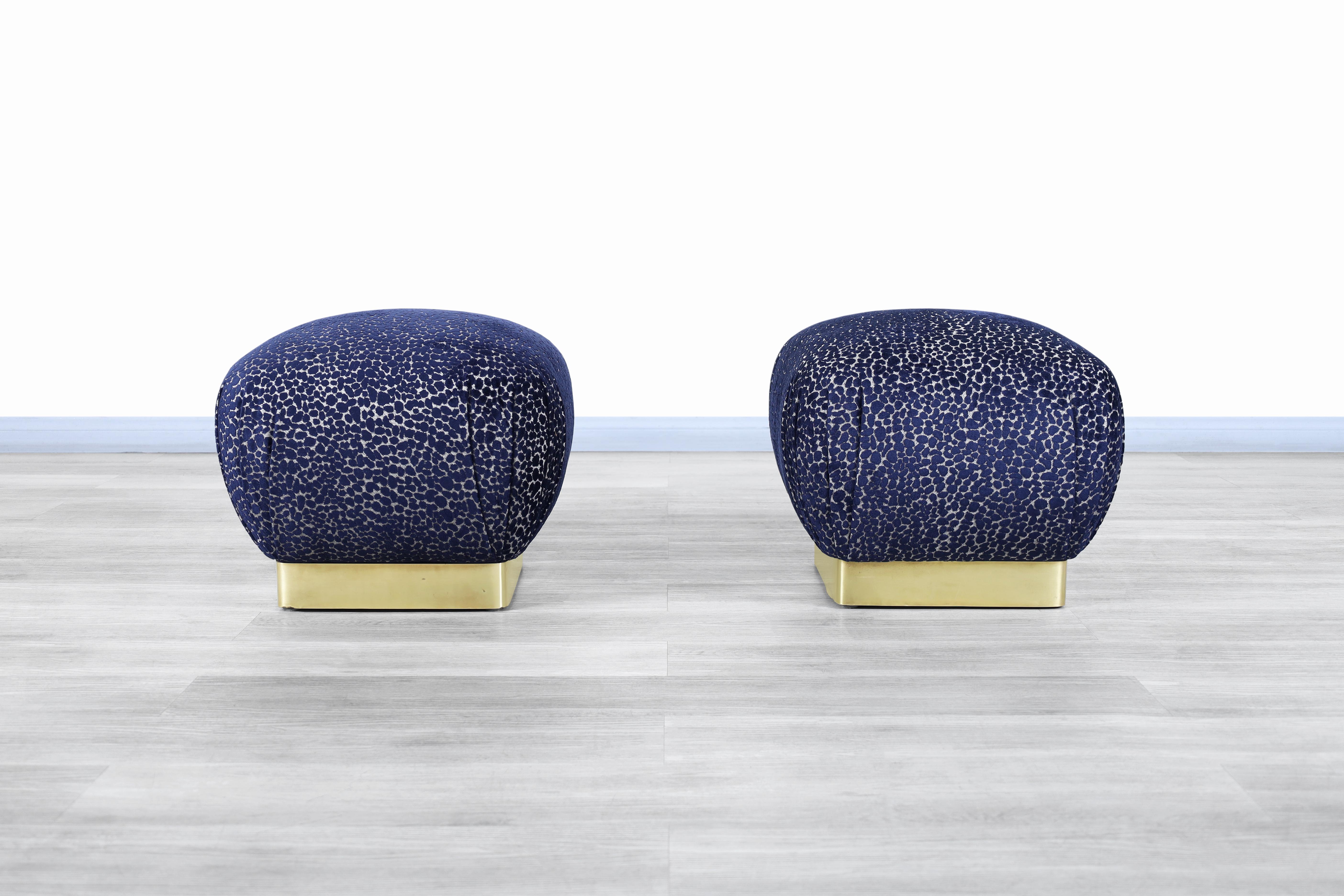 Wonderful pair of vintage brass poufs / ottomans designed by Marge Carson in United States, circa 1970s. These poufs have been professionally reupholstered in custom velvet. Each pouf features a brass base, making it stand out even more for its