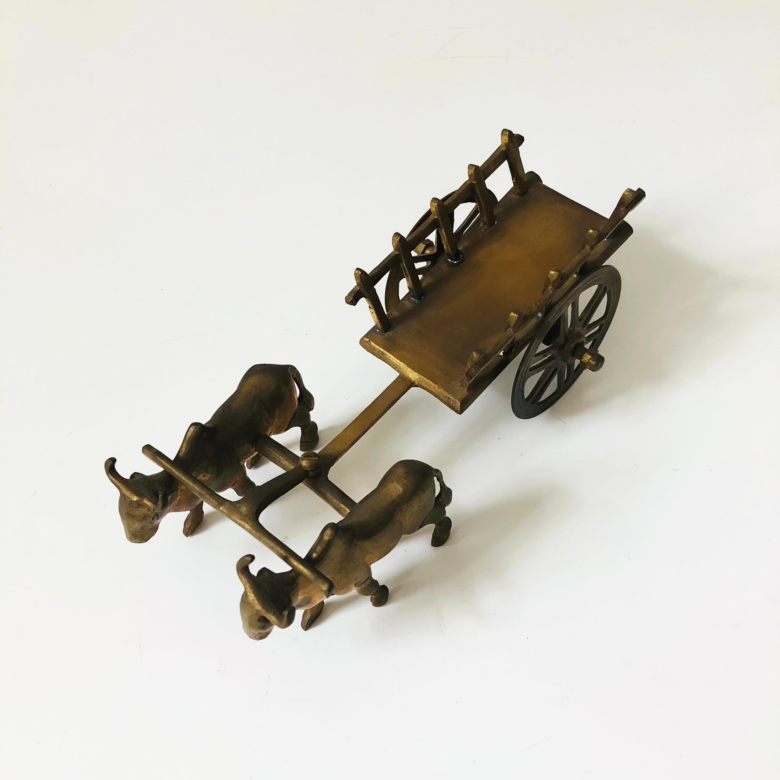 A pair of vintage brass oxen pulling a cart.

