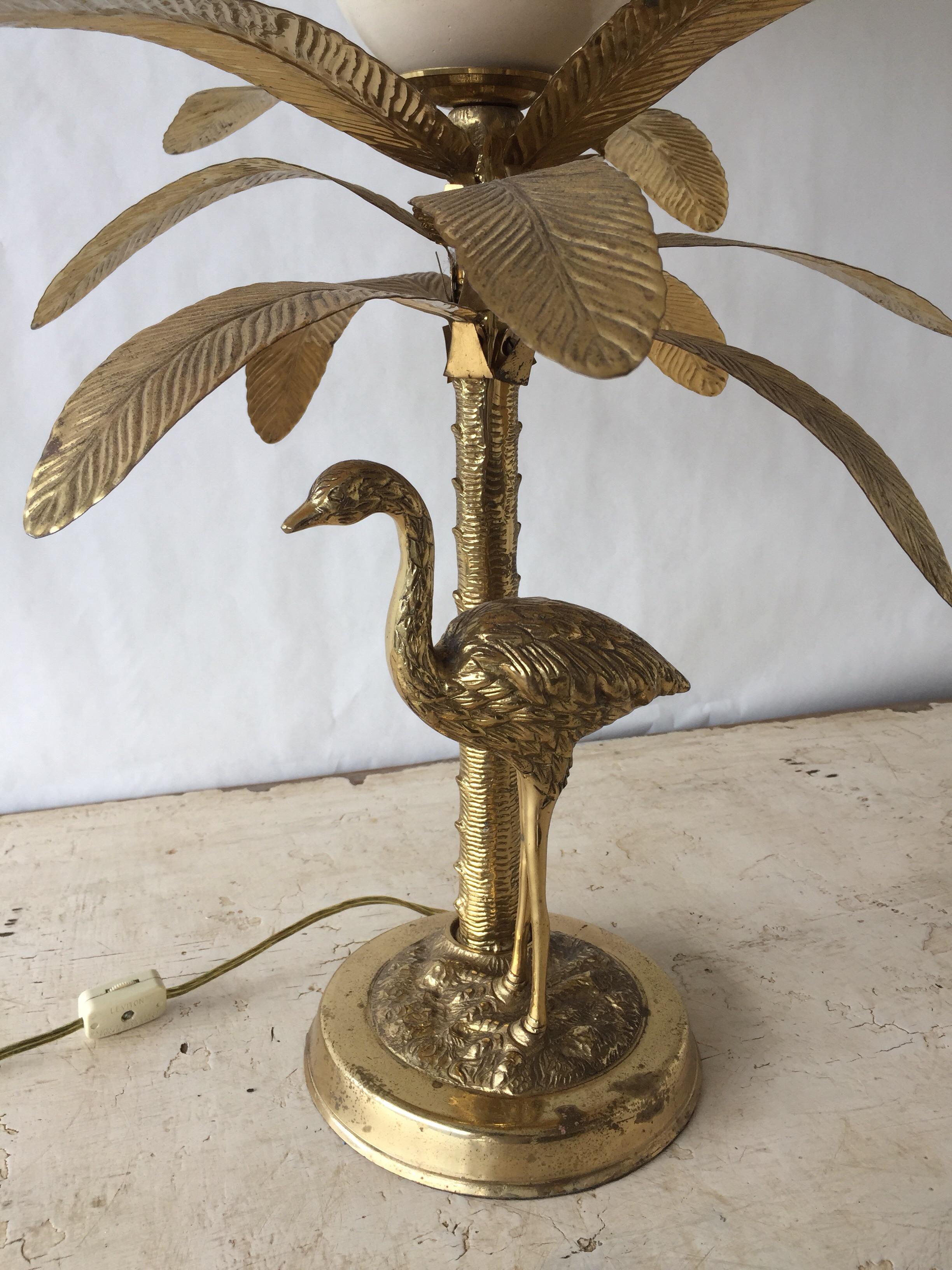 A stunning Hollywood Regency style lamp in brass, quite substantial and will surely be a conversation piece in any home. Cast in solid brass and features an enameled brass faux ostrich egg atop of an ostrich perched below a palm tree.

Note: Lamp