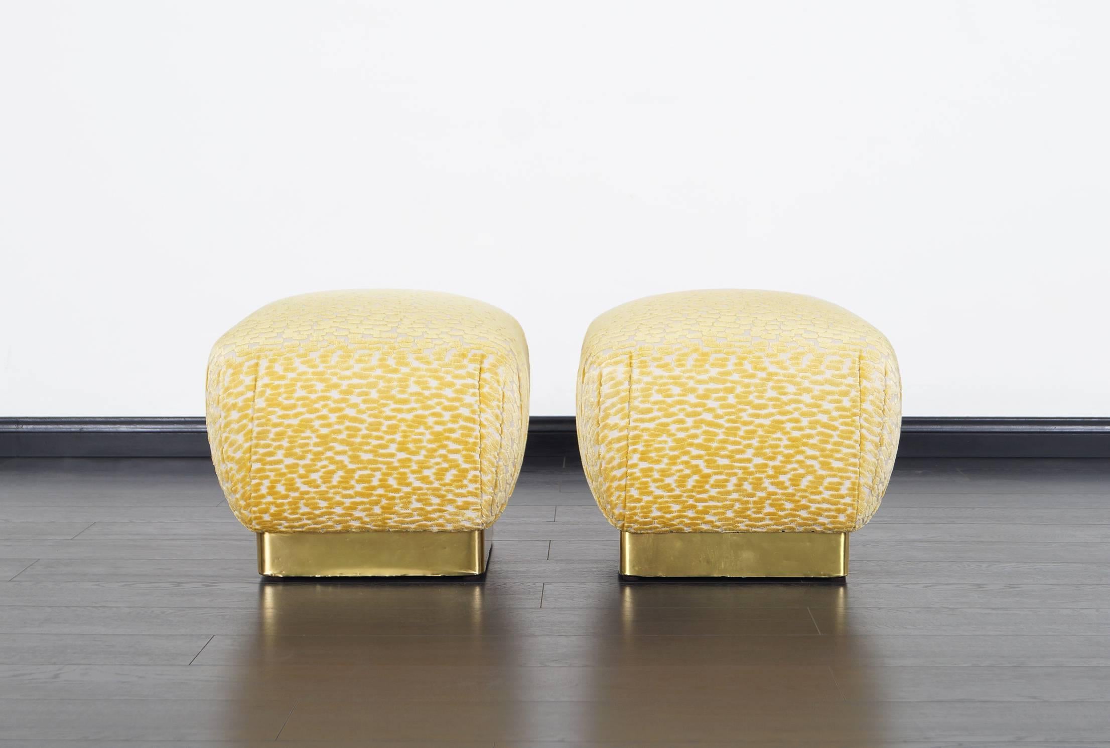 Stunning pair of vintage brass poufs / ottomans designed by Marge Carson. Newly reupholstered in custom velvet. The cushions pops up like a souffle. A great set for extra seating.