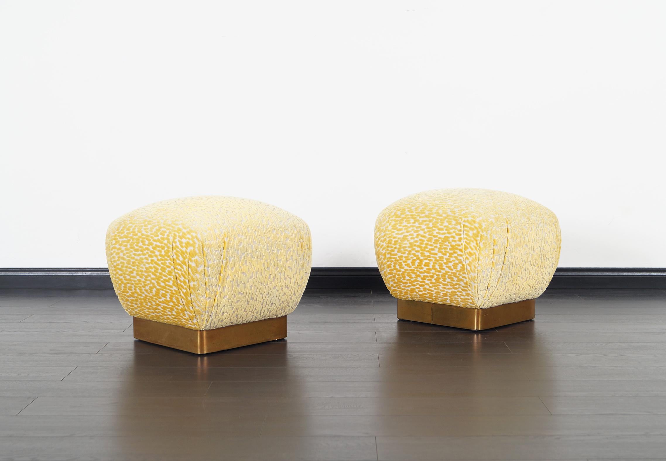 Wonderful pair of vintage brass poufs / ottomans designed by Marge Carson in United States, circa 1970s. These poufs have been professionally reupholstered in custom velvet. Each pouf features a brass base, making each pouf stand out even more for