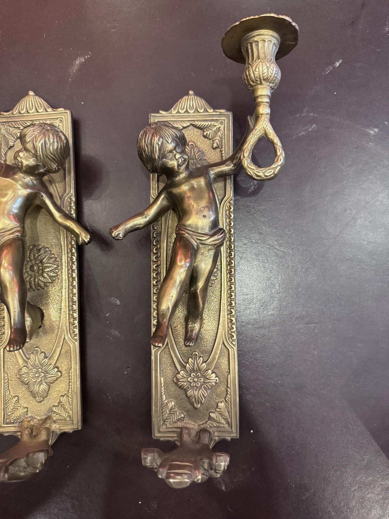 Vintage Brass Putti Cherub Angel Wall Mounted Sconces Candle Holders - Set of 2

These matching cherub wall sconces can hold small taper candles. The cherubs are mounted upon a rectangular background with flower and leaf patterns. Hang these sconces