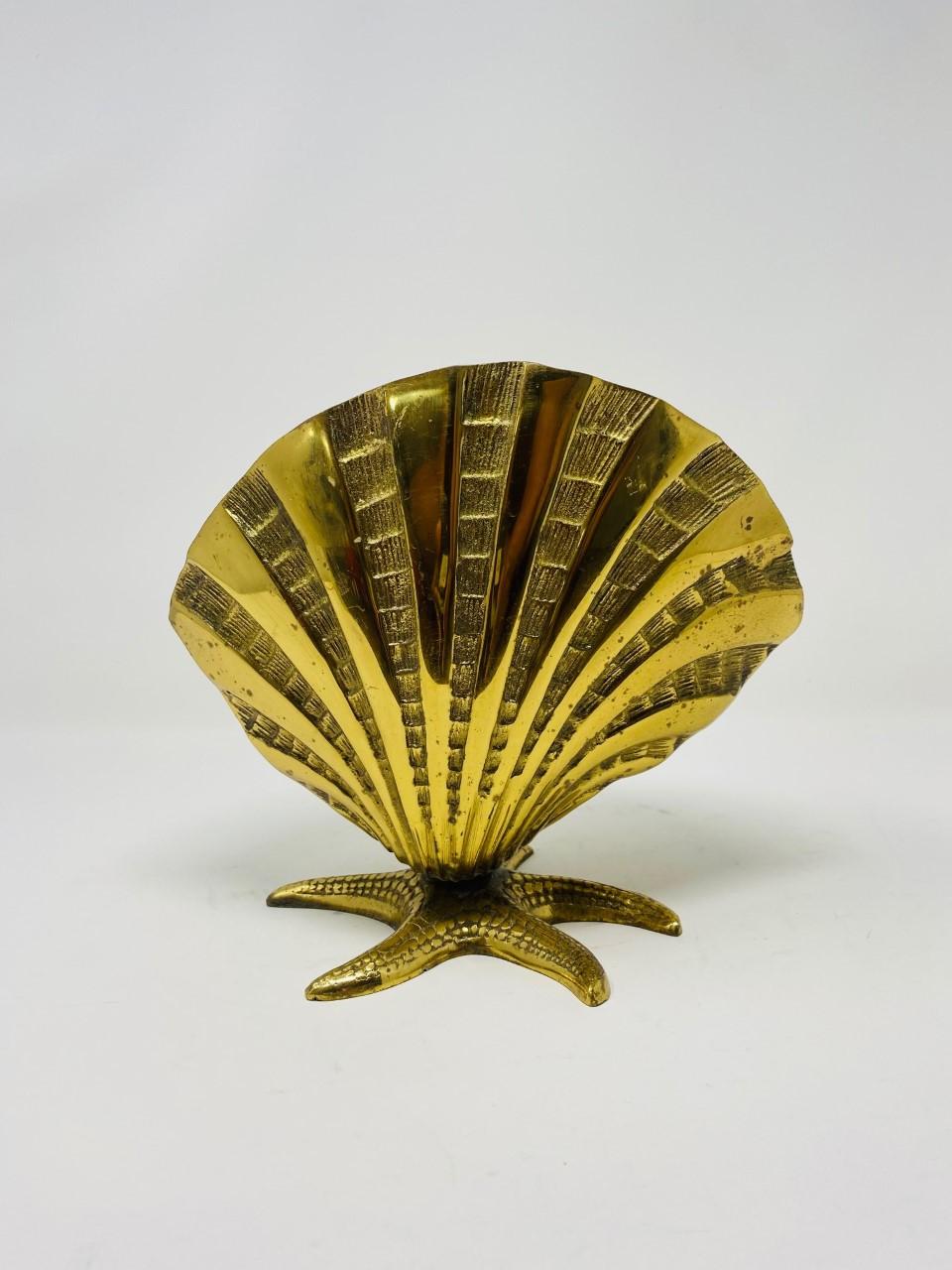 Sculptural and incredibly chic plant holder. This beautiful piece is rendered as a seashell. This mid-century piece is completed in brass and brings old Hollywood style to mind. The sculpted shell rests over a starfish that balances and stands the