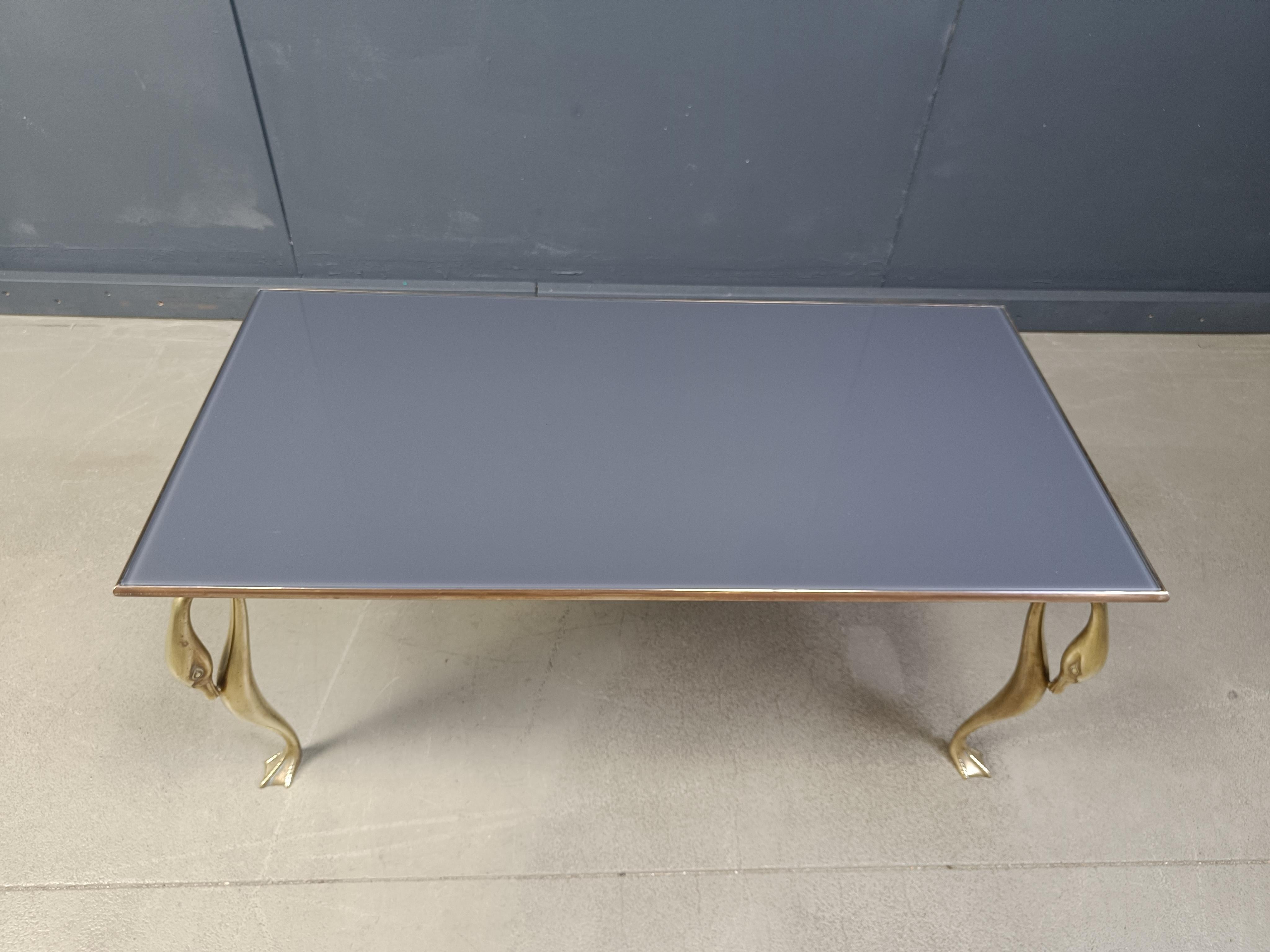 Hollywood regency brass swan coffee table.

The coffee table consists of 4 elegant brass swan shaped legs supporting a brass frame with inlaid grey glass.

Diemensions:
Height: 46cm
Width: 103cm
Depth: 51cm

Ref.: 25062309

*All images are always