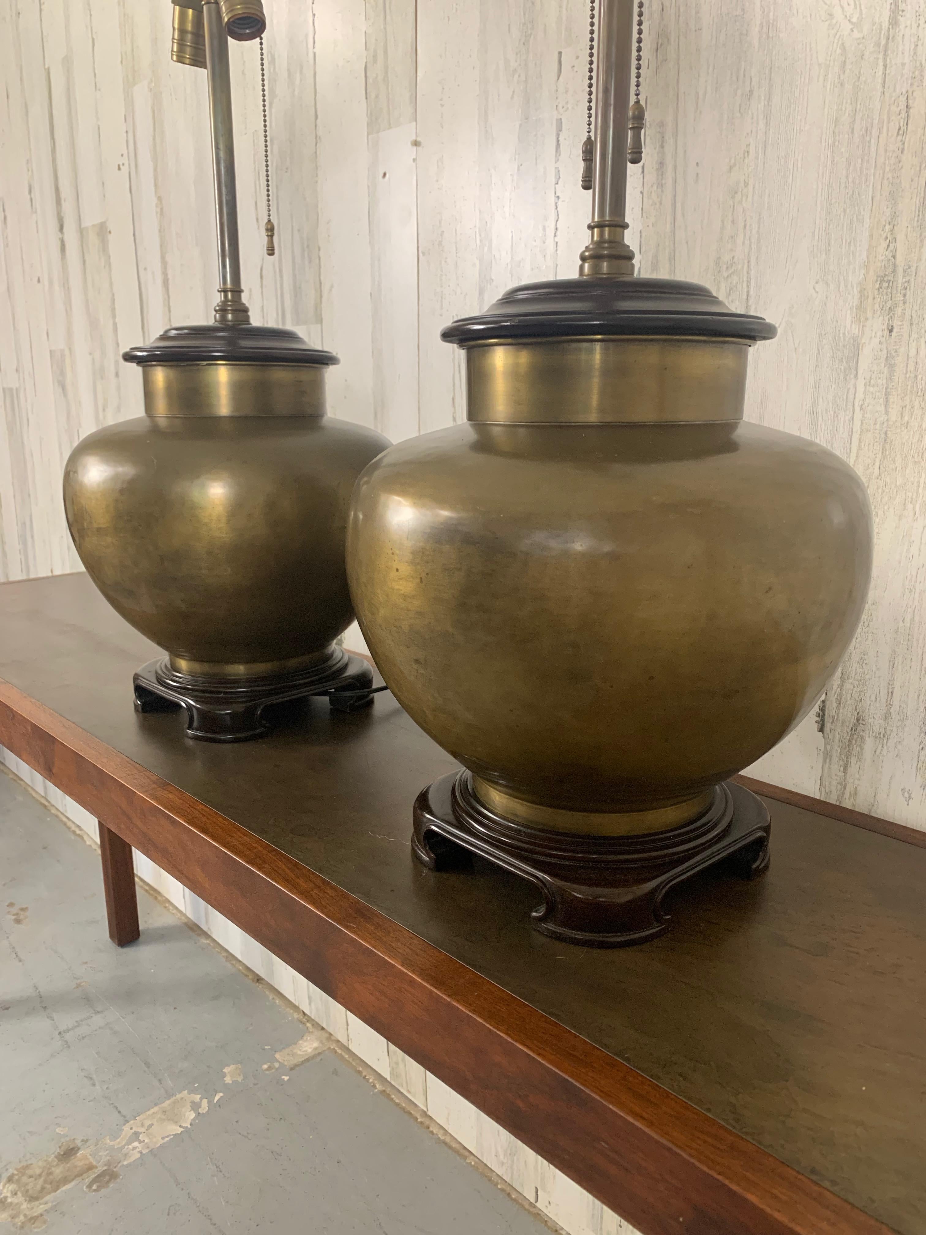 Nice pair of vintage brass with wood plinth and cap ginger jar table lamps.
The patina on the brass and wood give it a great vintage presence. 
There are no shades included.