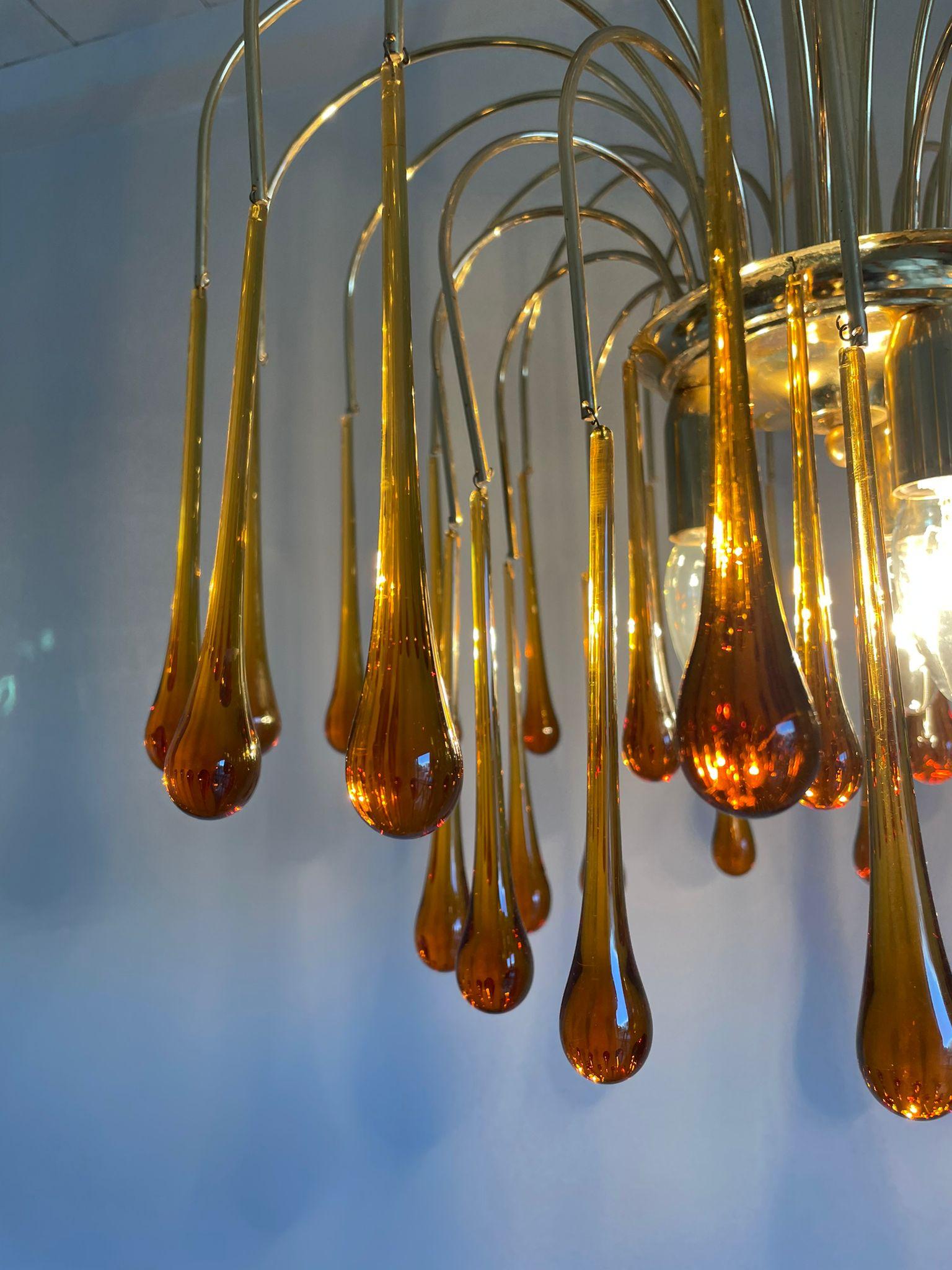 Elegant brass and amber coloured murano crystal chandelier.

The lamp is decorated with handblown murano teardrop glasses.

The chandelier emits a stunning light.

The lamp is fitted with 3 E27 light sockets.

1970s - Italy

Height: