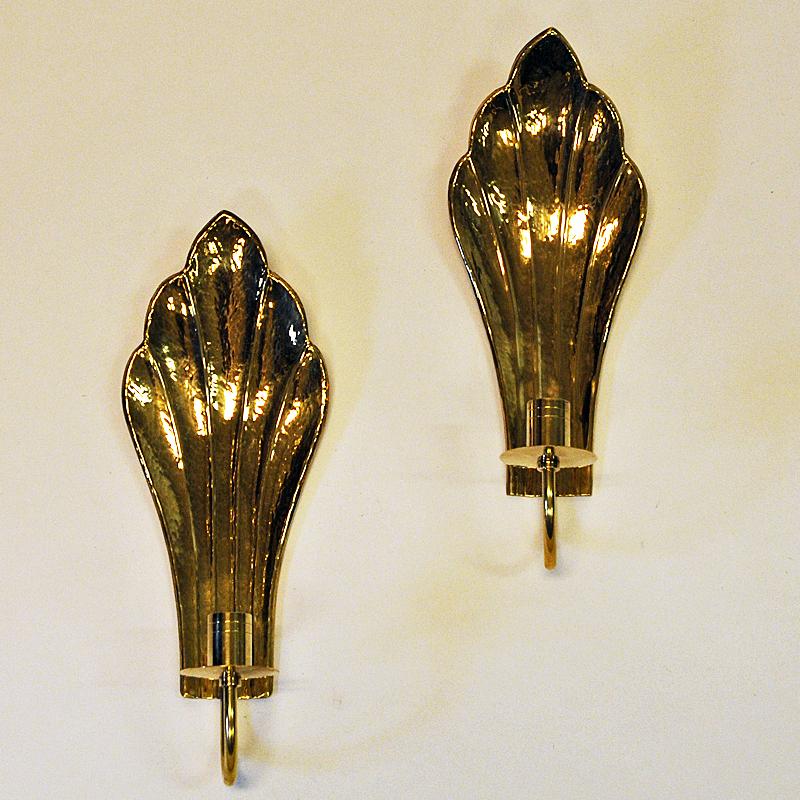 Very nice midcentury brass candlestick holders shaped as two leaves by Swedish designer Lars Holmström, Arvika, Sweden, 1960s. The holders are for wall hanging and they give a nice shine when a candle is lit. Stamp on the back with Lars Holmström,
