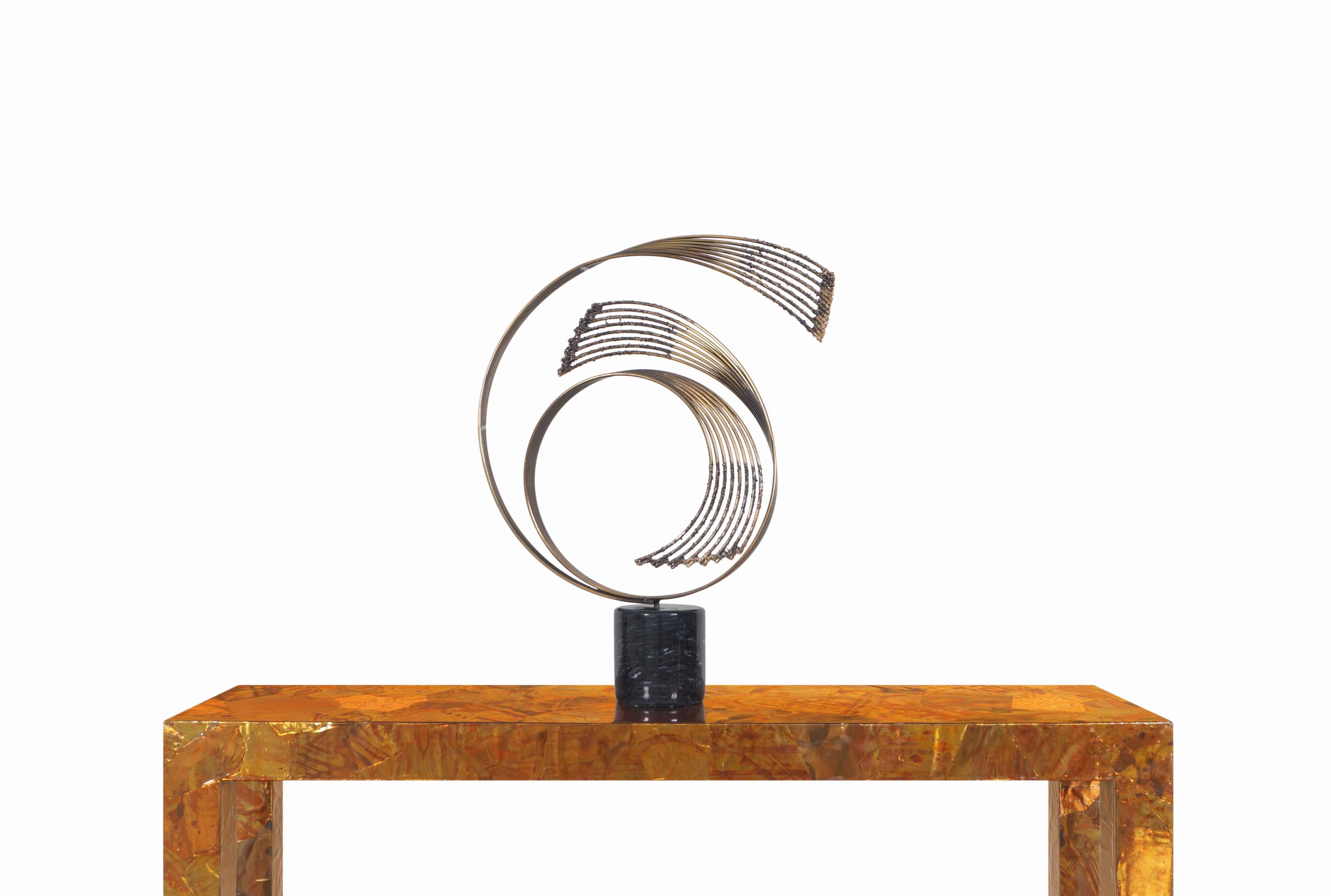 Stunning vintage brass “Windswept” sculpture designed by Curtis Jere and manufactured in the United States. At the top, we have an elegant representation of abstract art where its circular composition made up of brass-plated metal rods stands out.