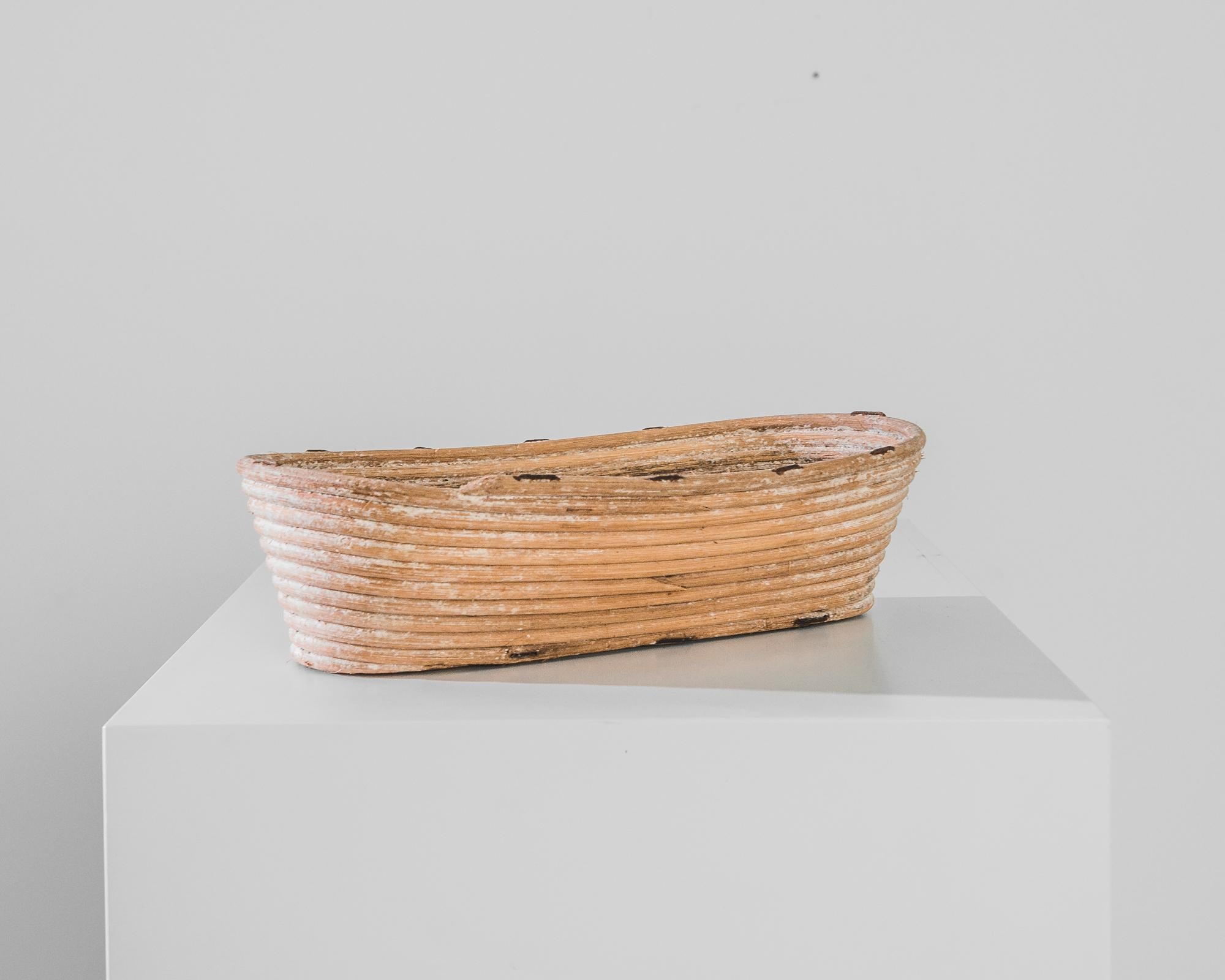 A boat-shaped wicker basket handcrafted in Czechia circa 1900. An essential tool from a bustling early 20th Century bakery. Three inches tall and 17 inches wide, sized just right for the daily loaf.