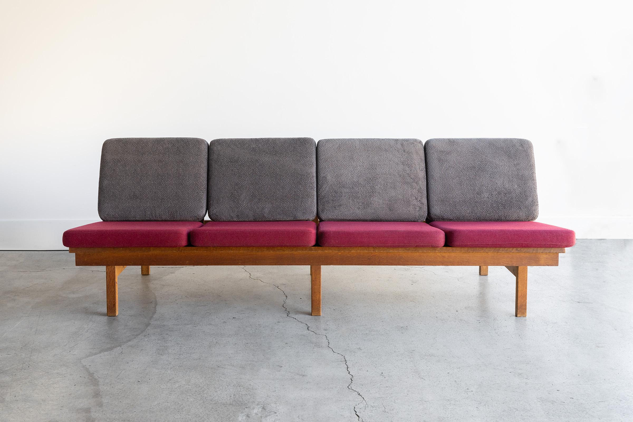A stunning example of mid century simplicity. Børge Mogensen for Fredericia Stolefabrik 4 seat sofa model 2219. Featuring a solid oak frame with two tone cushions 4 red, 4 grey with a beautiful pattern. Upholstery is in great condition as is the