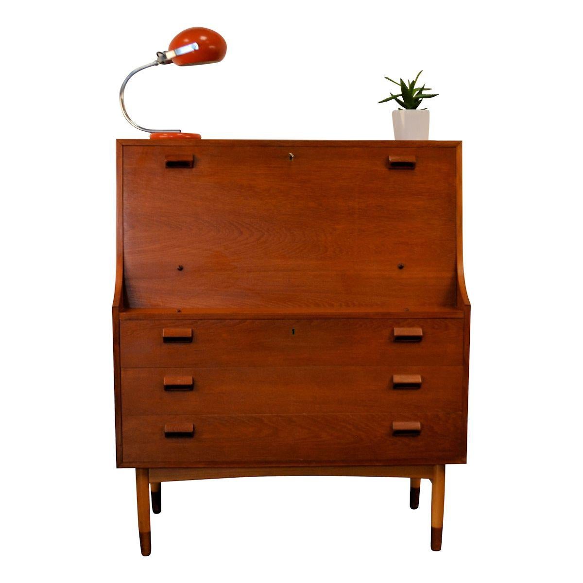 Mid-Century Modern Danish cabinet desk designed Børge Mogensen for Søborg Møbelfabrik in the 1960s. The hinged shelf easily creates a desk area, ample storage space is provided by 3 spacious drawers below the desk area, 2 smaller drawers an storage