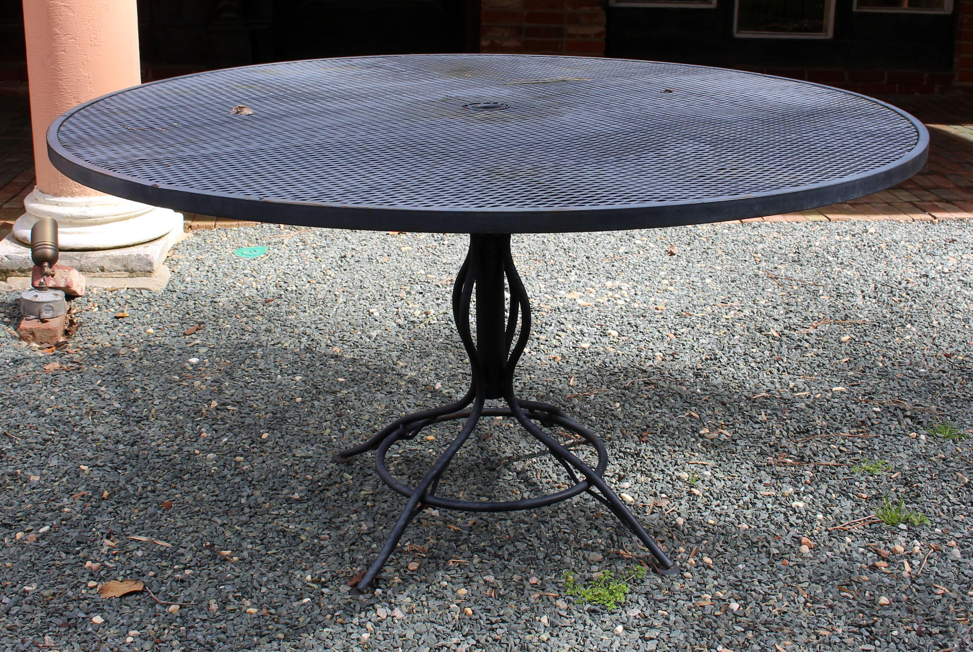 Vintage Woodard outdoor table & 4 barrel back chairs, Briarwood pattern, not labeled. Two spring chairs & two standard chairs. Large, stable umbrella stand table with scrolled iron supports around the umbrella holder. Weathered patina.
Table: 53.5