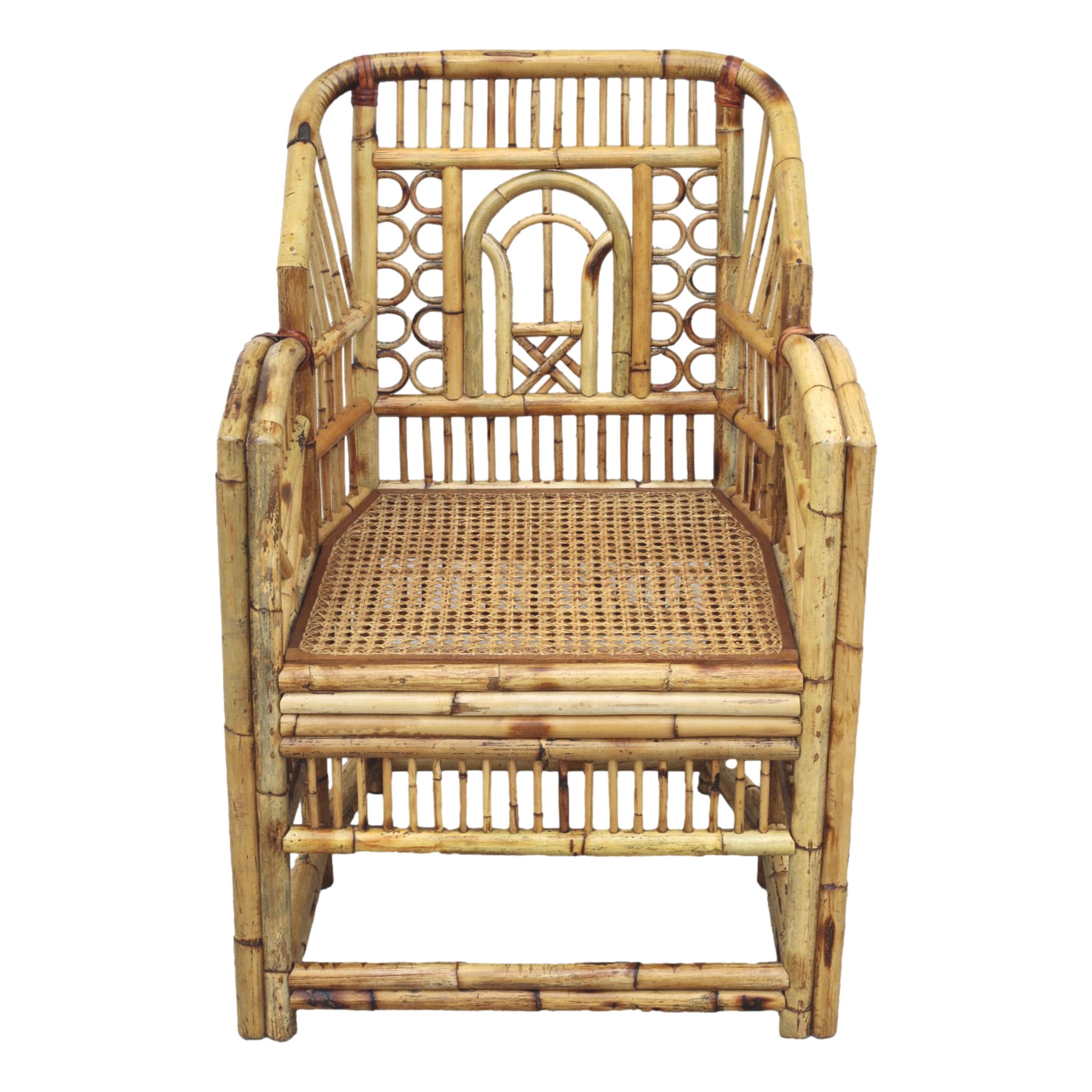 Brighton style bamboo dining arm chair, circa 1970.  This handcrafted Chinese Chippendale chair features a caned-bottom seat, bamboo open fretwork, and a burnt bamboo finish with a lovely distressed aged patina. Small loss of bamboo fretwork as