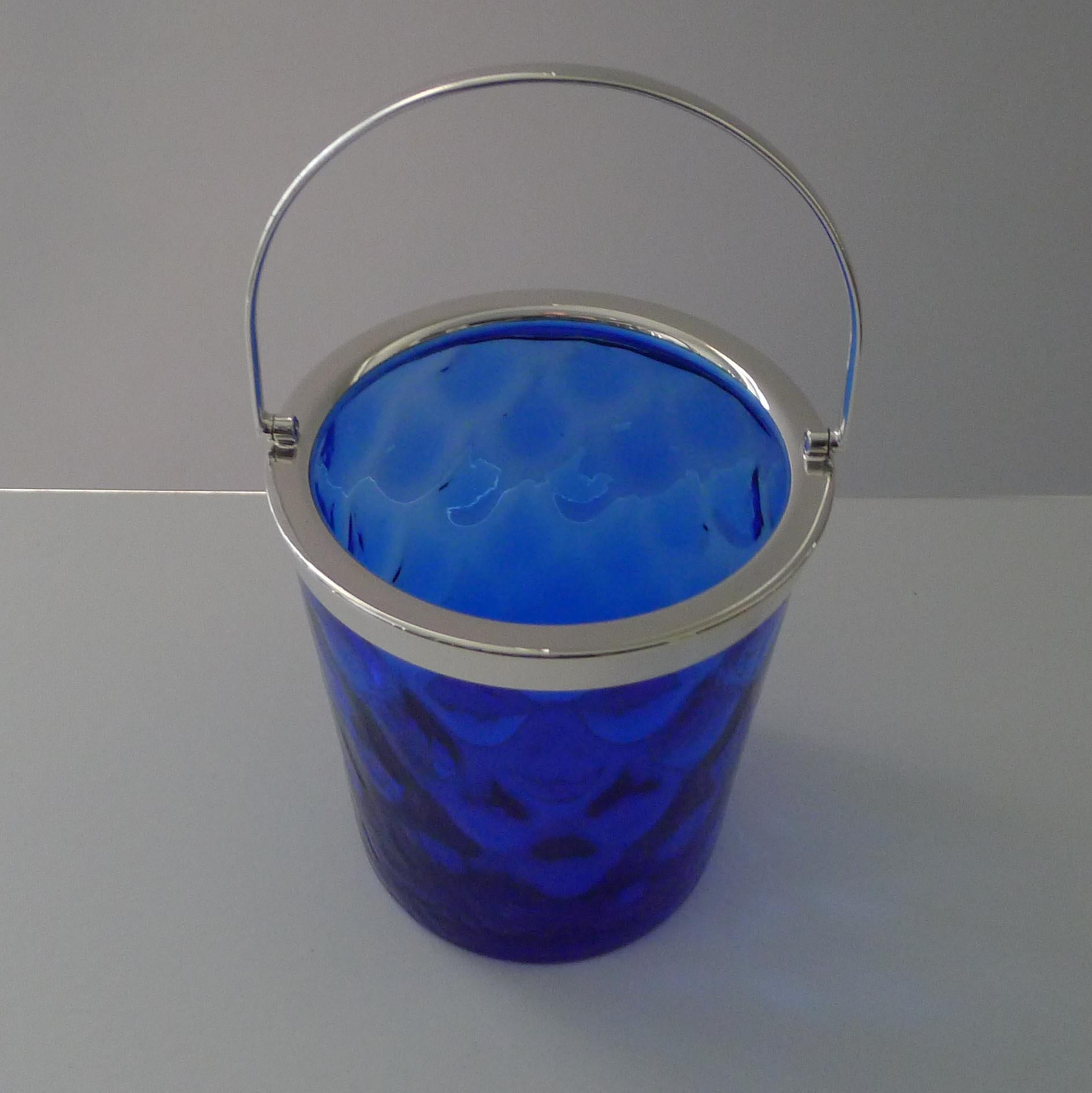 A handsome vintage ice bucket made from hand-blown Bristol blue glass with a polished pontil mark on the underside.

The glass has a rippled design and the fittings made from silver plate.  No marks, English in origin and dating to the