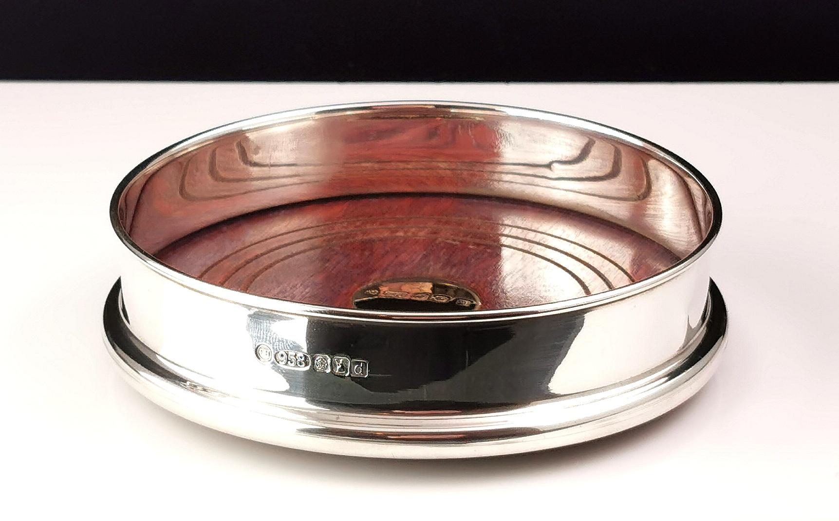 A very fine vintage Britannia silver wine or bottle coaster.

Made from 958 silver with a hardwood base set with a 9ct yellow gold roundel to the centre.

The base is covered with a green felt to protect the surface it stands on.

It is a stylish