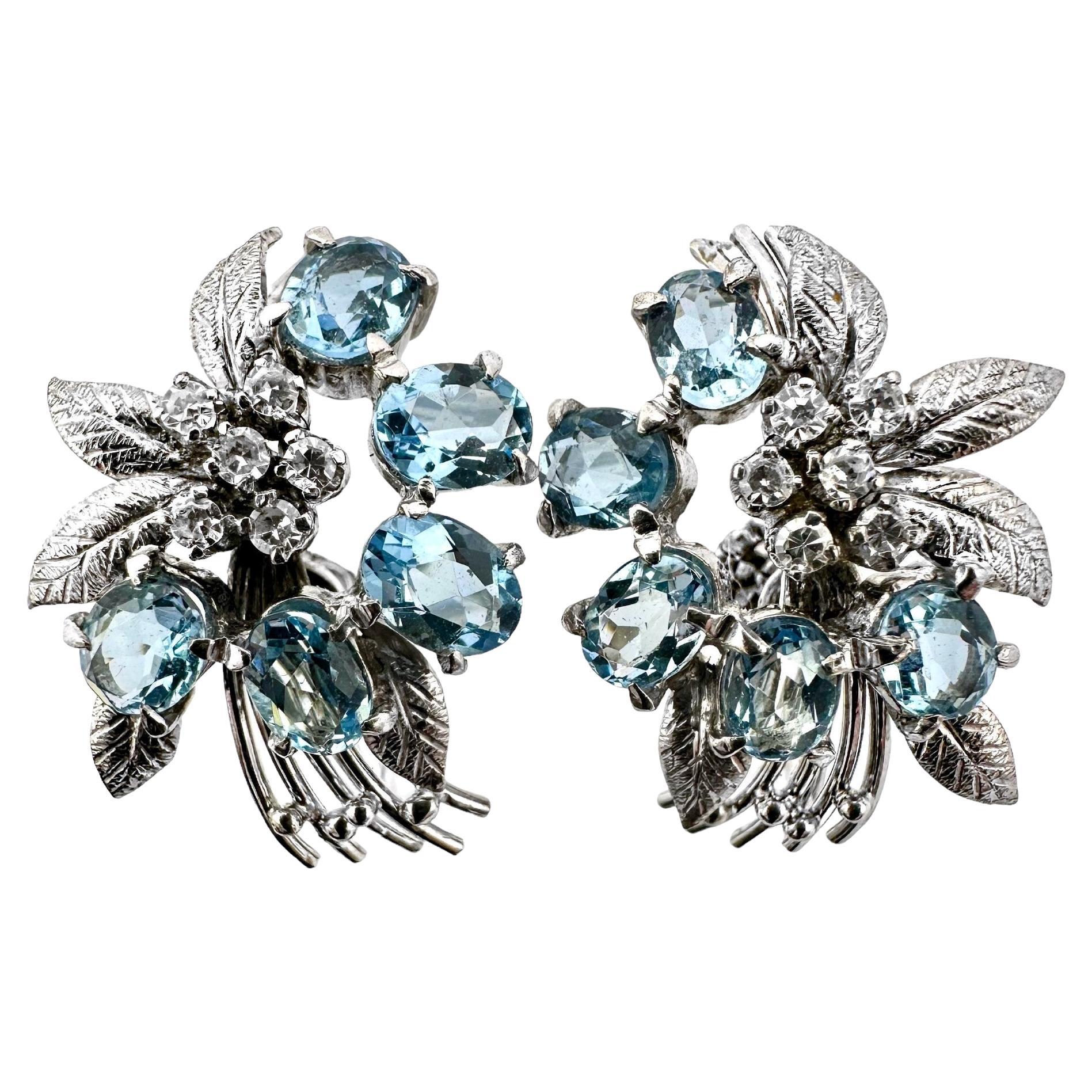 This absolutely charming pair of Mid-20th Century 18k white gold, Aquamarine and diamond floral bouquet clip on earrings are a true visual delight. Set with a total of ten oval aquamarine stones and twelve single cut diamonds, they have a wonderful