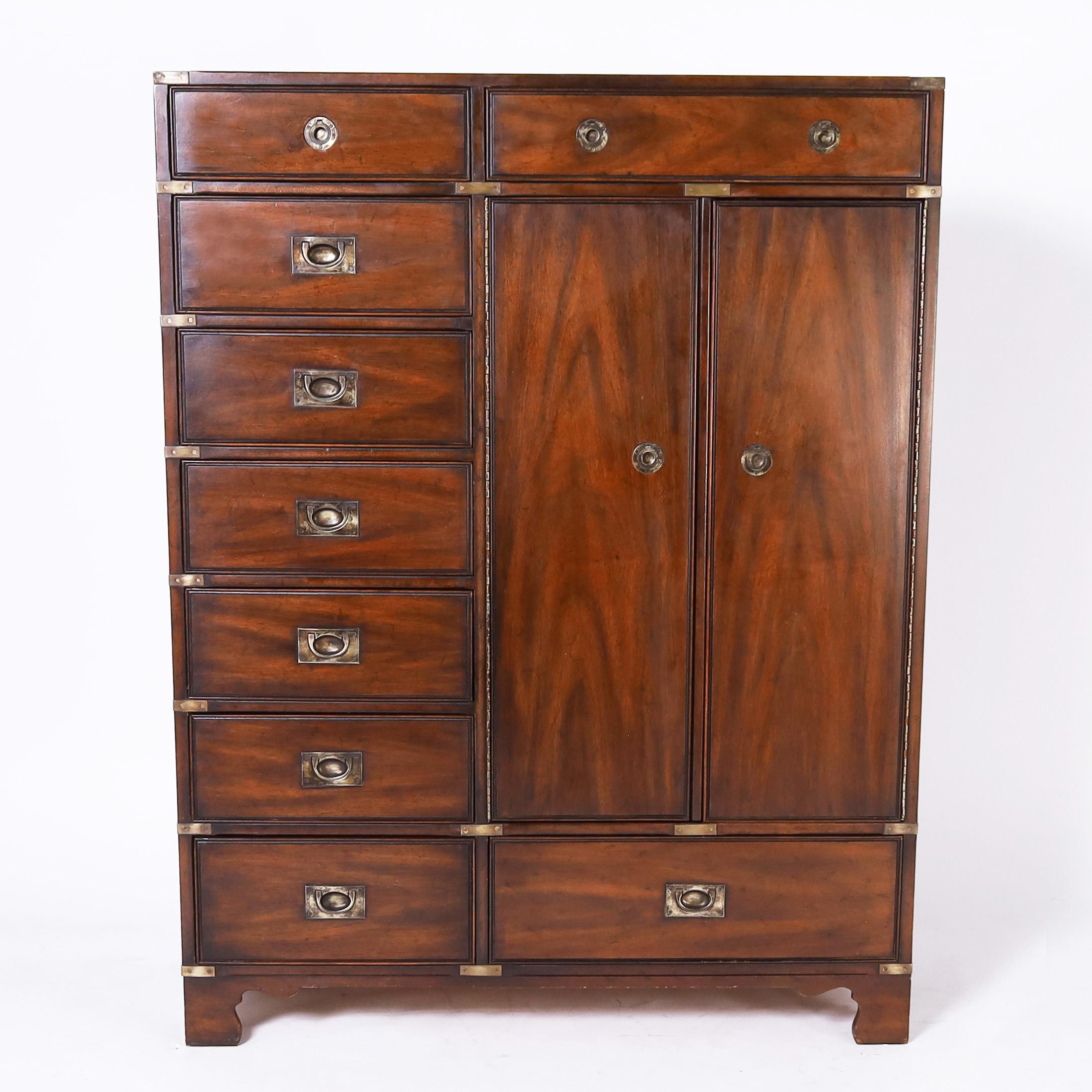Mid Century interpretation of a British colonial campaign gentleman's wardrobe crafted in mahogany having a lush dark finish, brass hardware, plenty of storage and classic bracket feet. Made by one of America's premiere furniture makers, signed