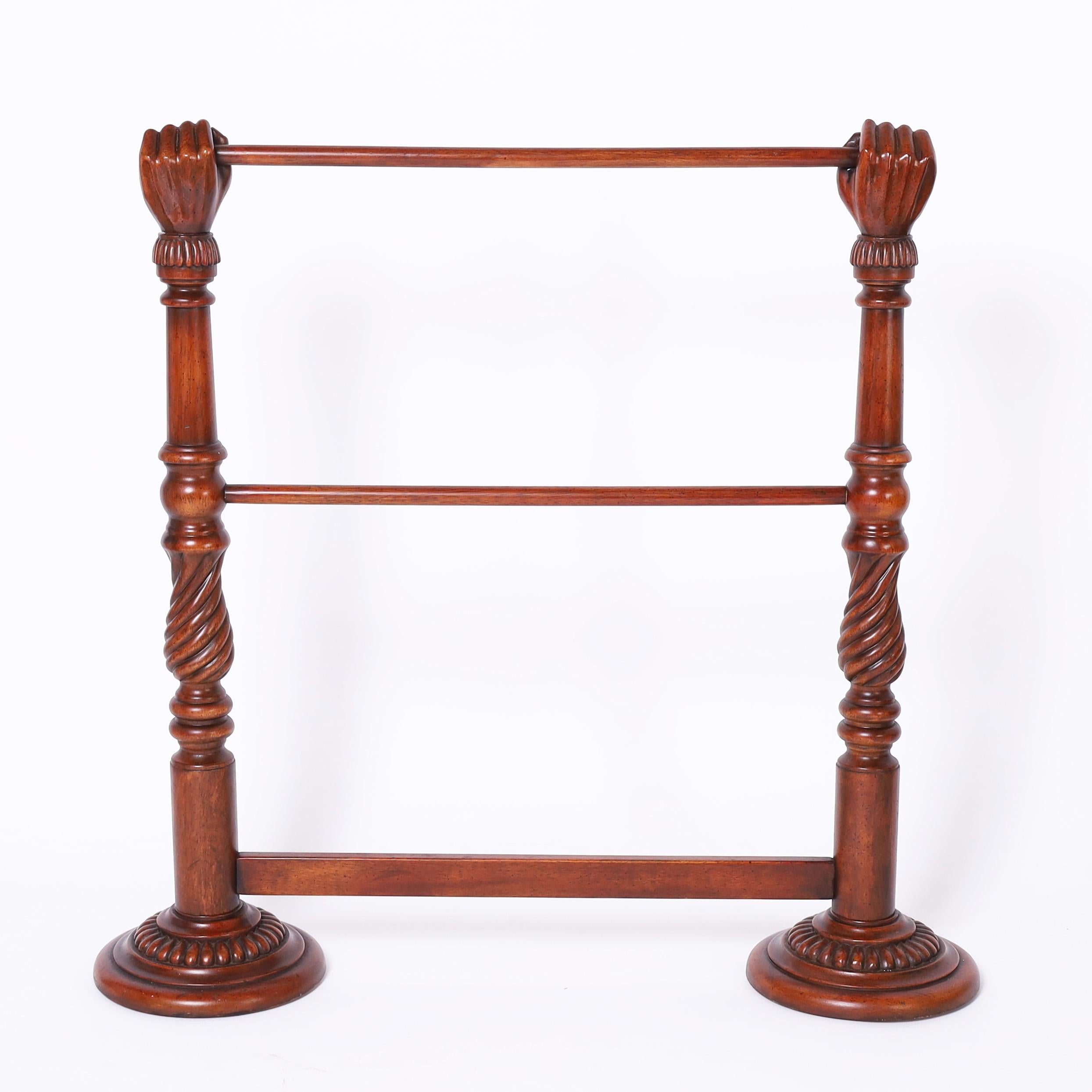 Standout vintage Anglo Indian blanket or display rack crafted in mahogany with a fly speck finish having two turned supports with carved fists at the top holding cross bars on turned and beaded bases.