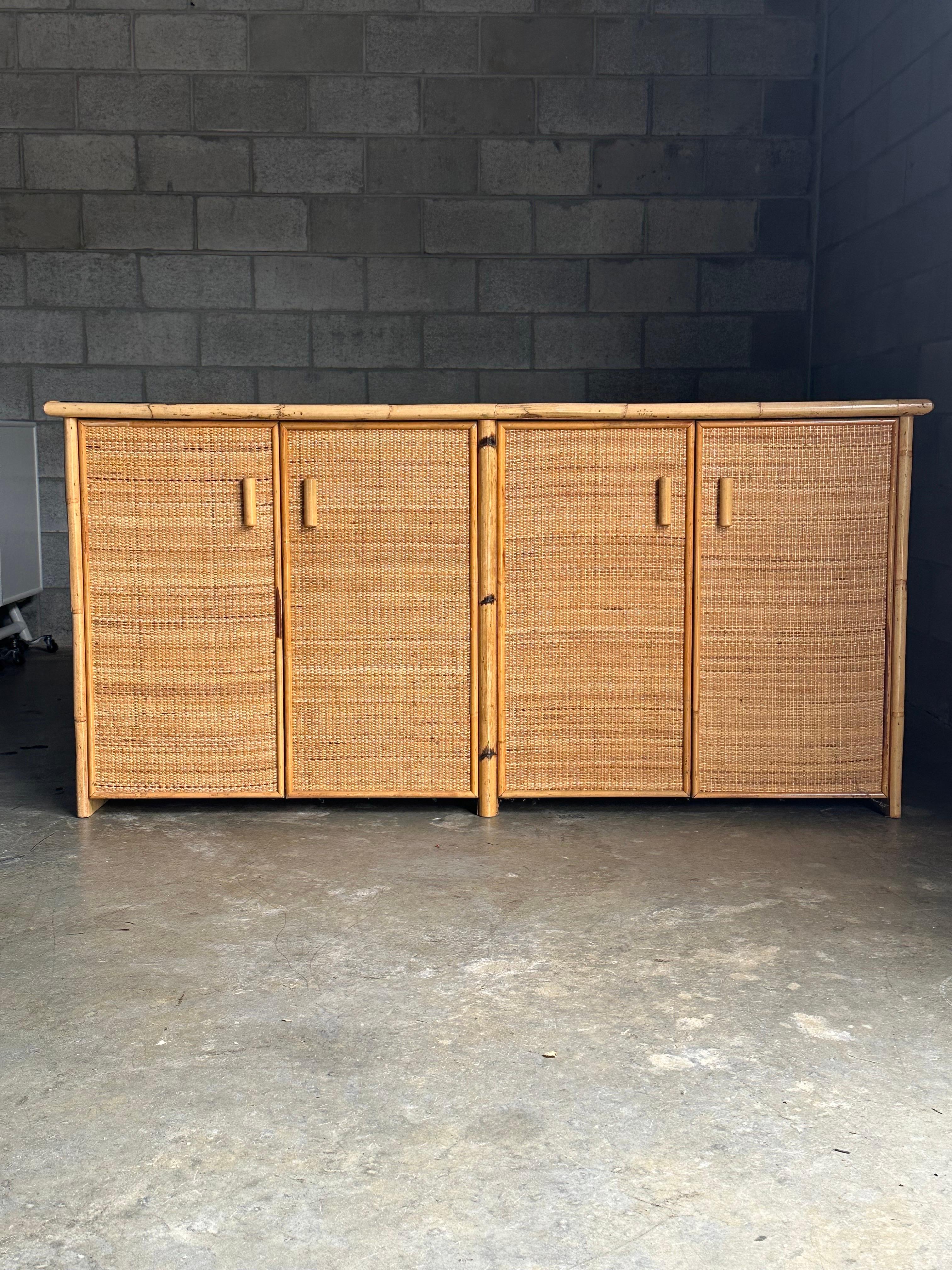 A very nice sideboard consisting of a bamboo frame with cane clad panels. Features four doors, each set revealing shelves. On the left is one adjustable shelf, and the right side has two shelves. Nicely proportioned at 16.75