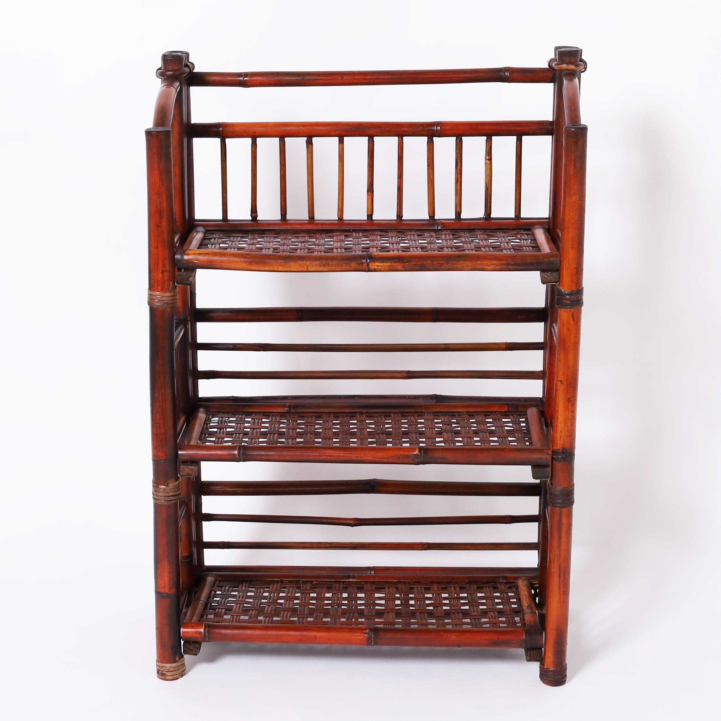 Etagere di metà secolo in stile British Colonial realizzata in bambù con tre ripiani in rattan intrecciato con un'ingegnosa opzione pieghevole.

H: 32 W: 22 D: 11
Profondità Foldes: 4