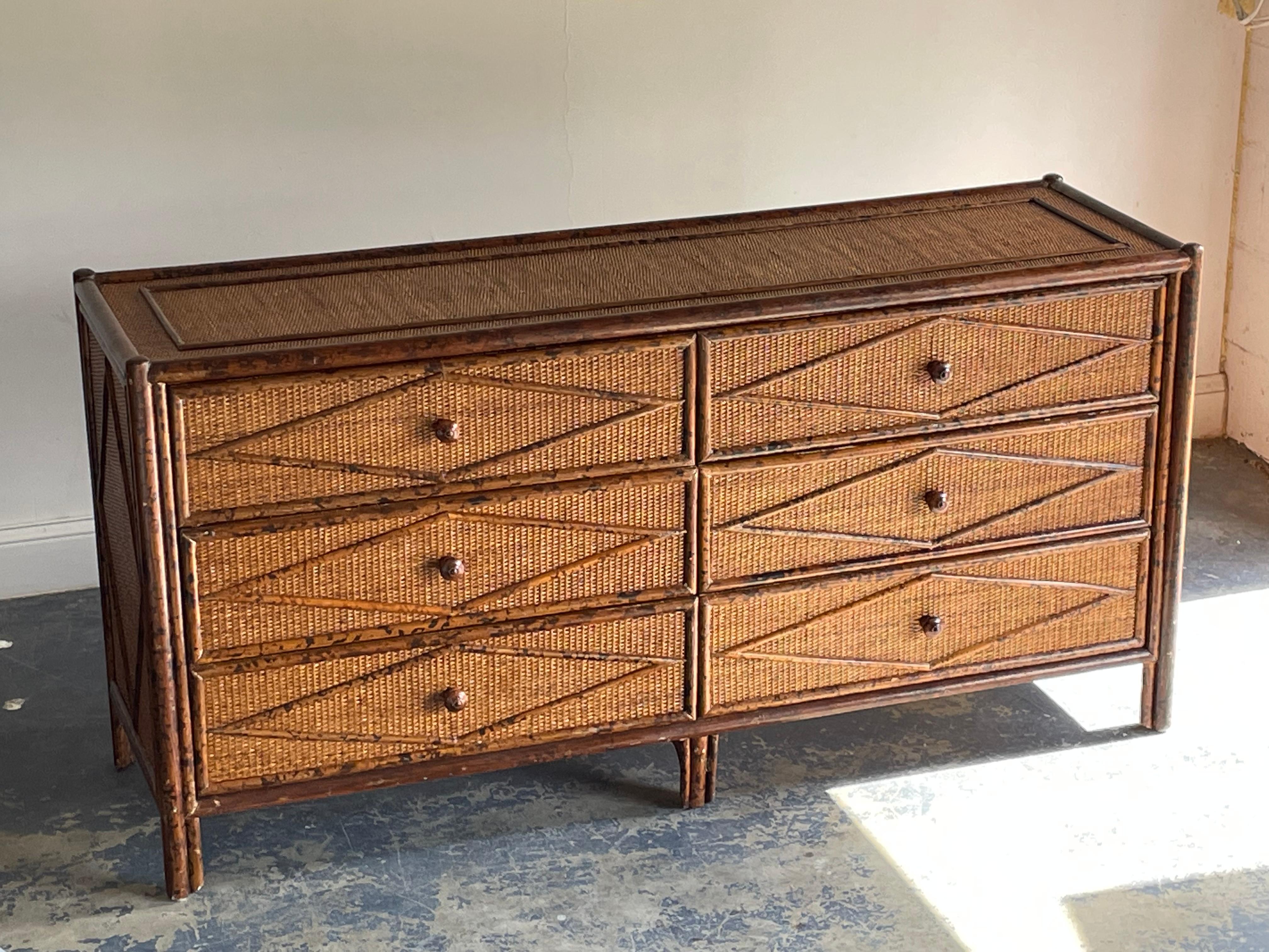 Vintage British colonial style dresser in bamboo and rattan. Six spacious drawers clad in rattan with a burnt or tortoise bamboo skeleton. Wonderful diamond pattern throughout.