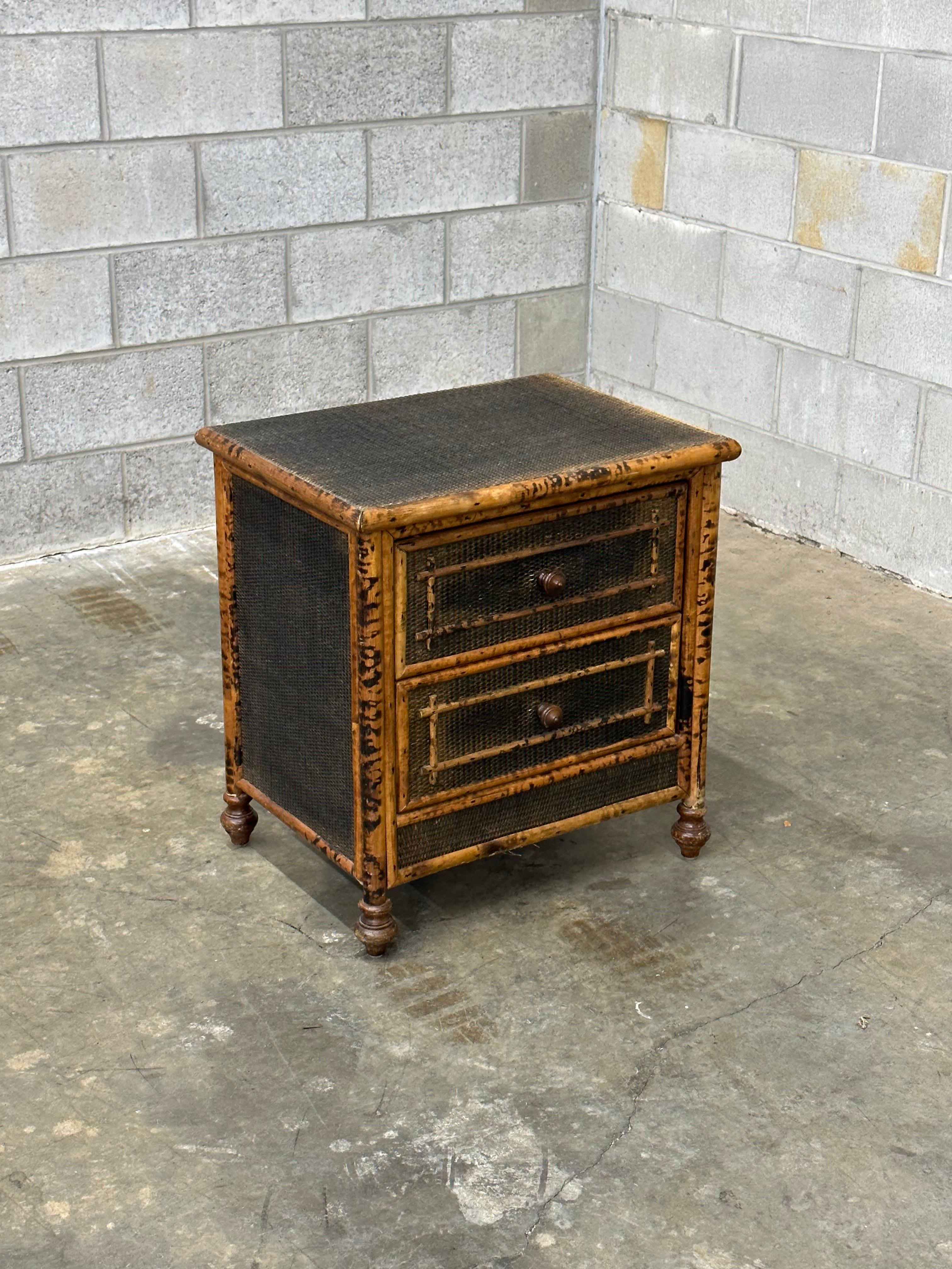 Vintage British colonial style nightstand or end table in bamboo and rattan. Two spacious drawers clad in rattan with a bamboo skeleton. Wonderful geometric pattern throughout. Would work in a variety of interiors. Design is attributed to Ralph