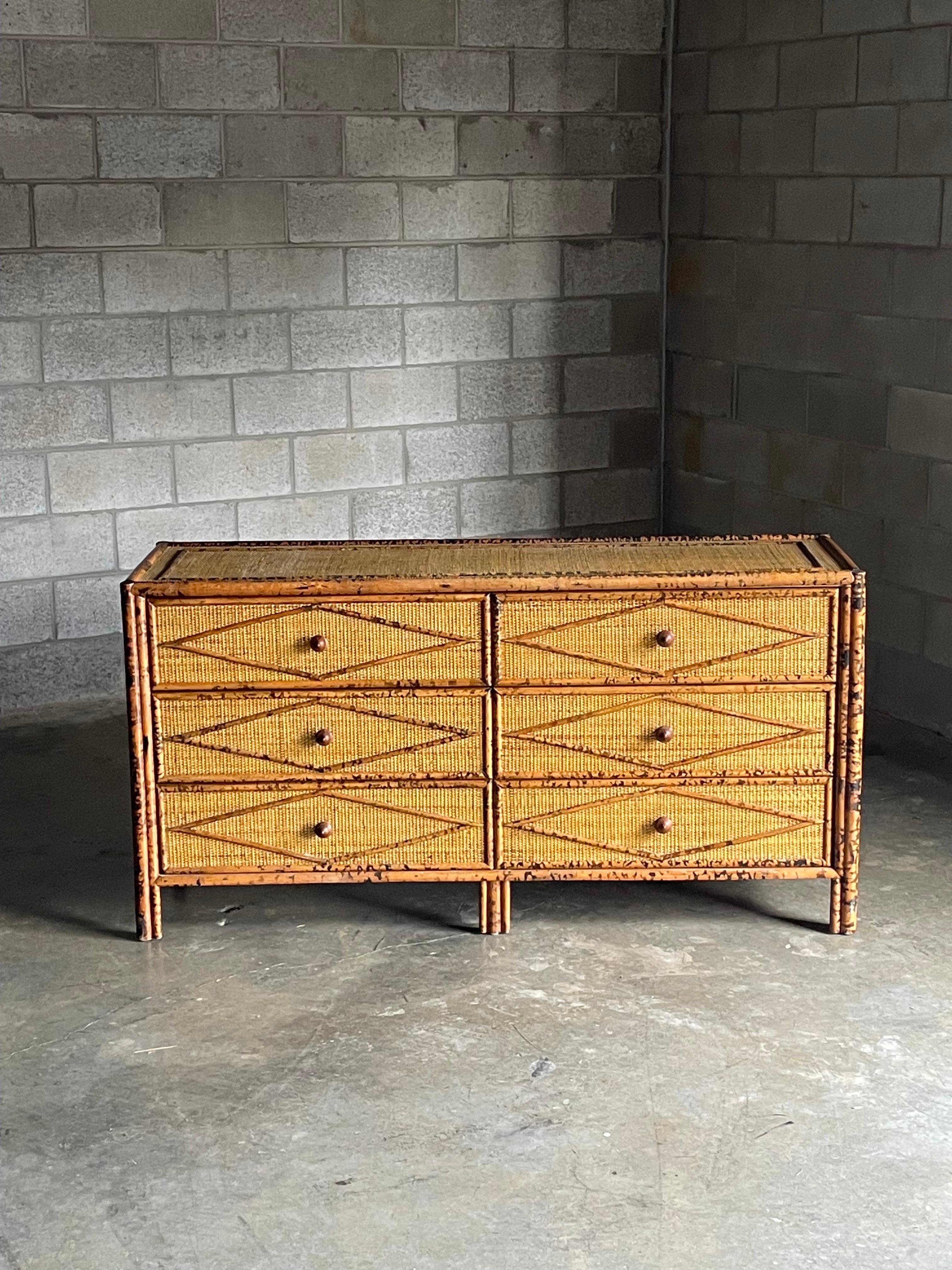 Vintage British colonial style dresser in faux burnt bamboo and rattan. Six spacious drawers clad in rattan with a bamboo skeleton. Wonderful diamond pattern throughout. Sold through Bloomingdales in the 1990s and attributed to Ralph Lauren, this