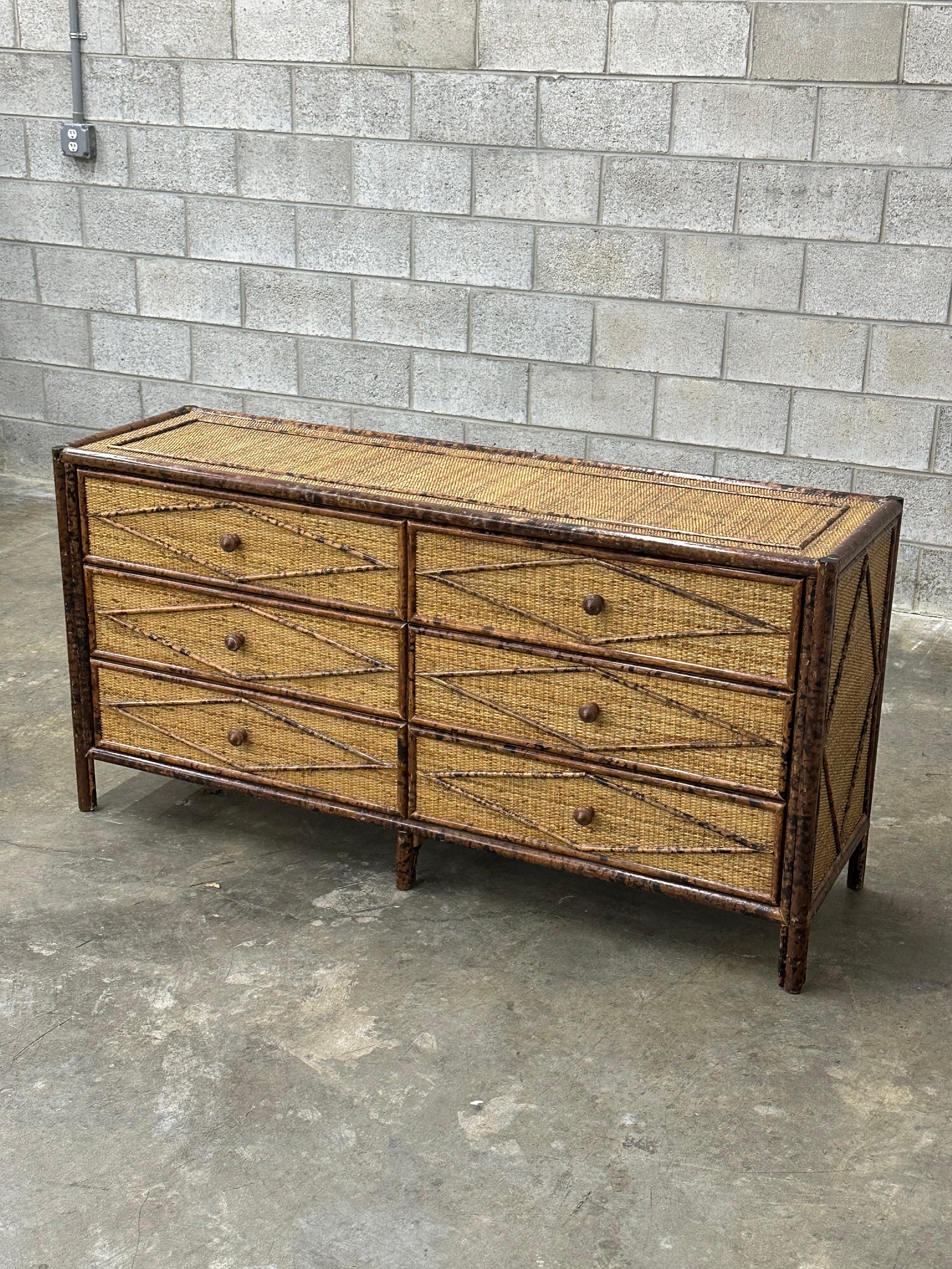 Vintage British colonial style dresser in bamboo and rattan. Six spacious drawers clad in rattan with a bamboo skeleton. Wonderful diamond pattern on drawer fronts and cabinet sides. Would work in a variety of interiors. 

Design is attributed to