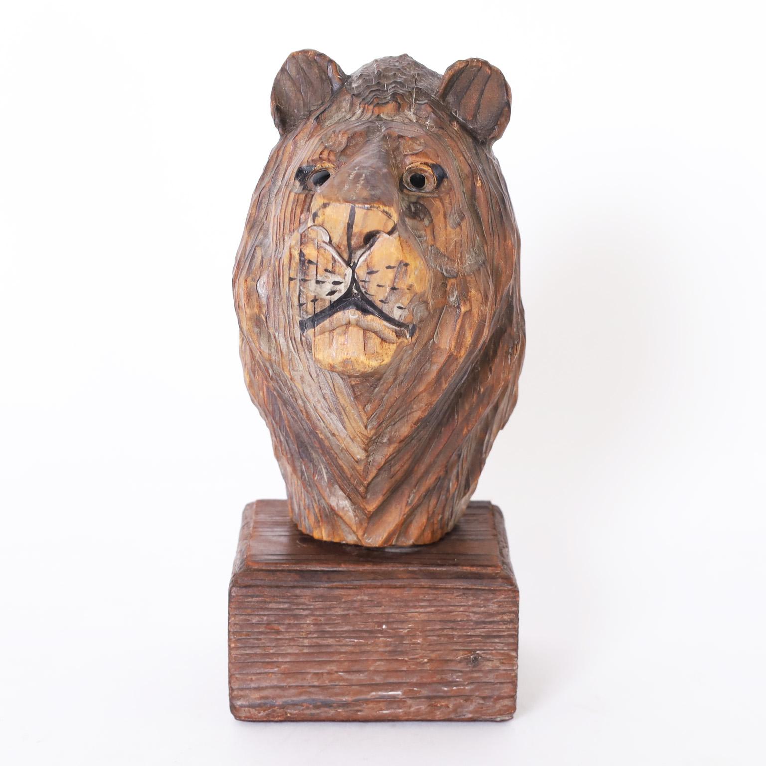 British colonial stylized carved wood lion head with glass eyes presented on a sculptural pine base.