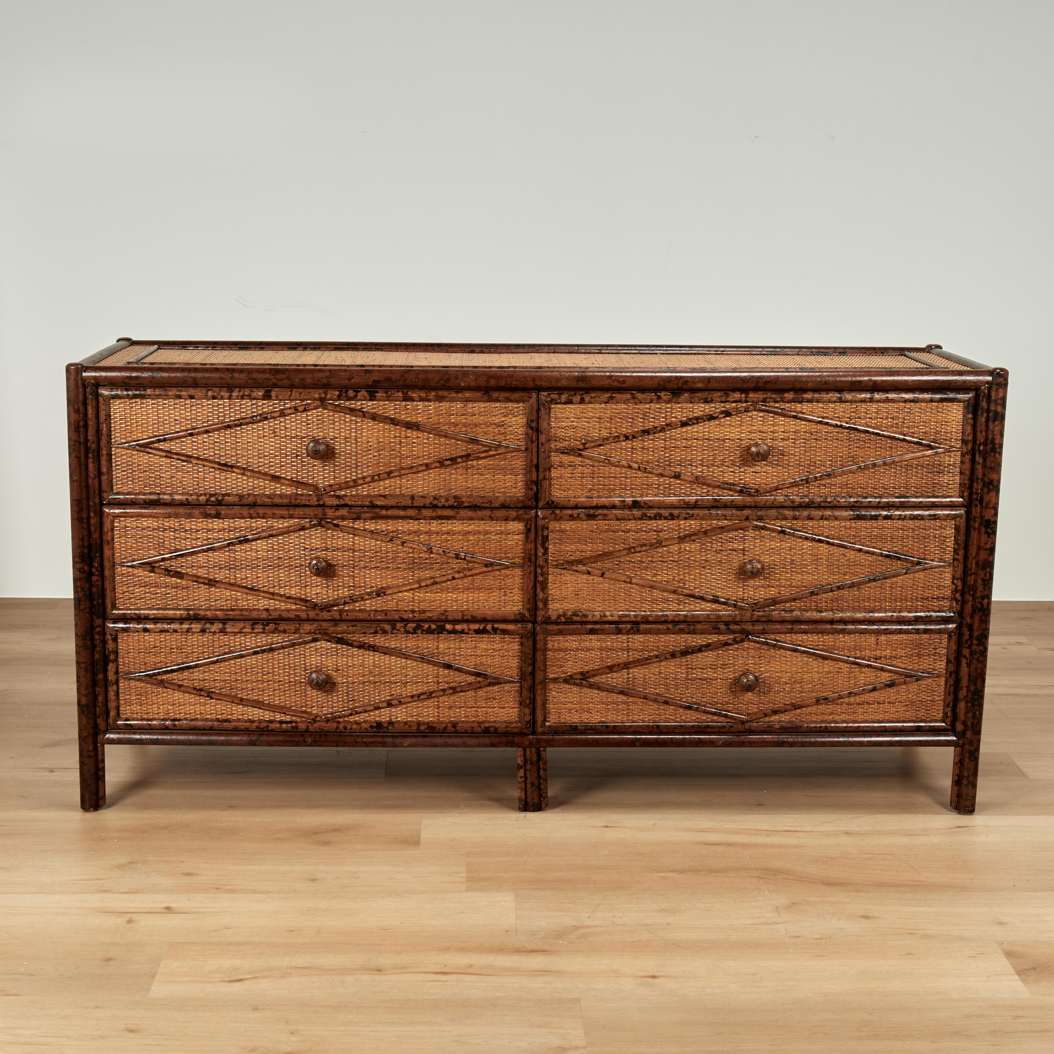 Bellissimo comò matrimoniale in stile British Colonial della metà del secolo, con struttura in finto bambù, finitura tartaruga e pannelli in tela d'erba tutt'intorno con disegni geometrici in finto bambù applicati.