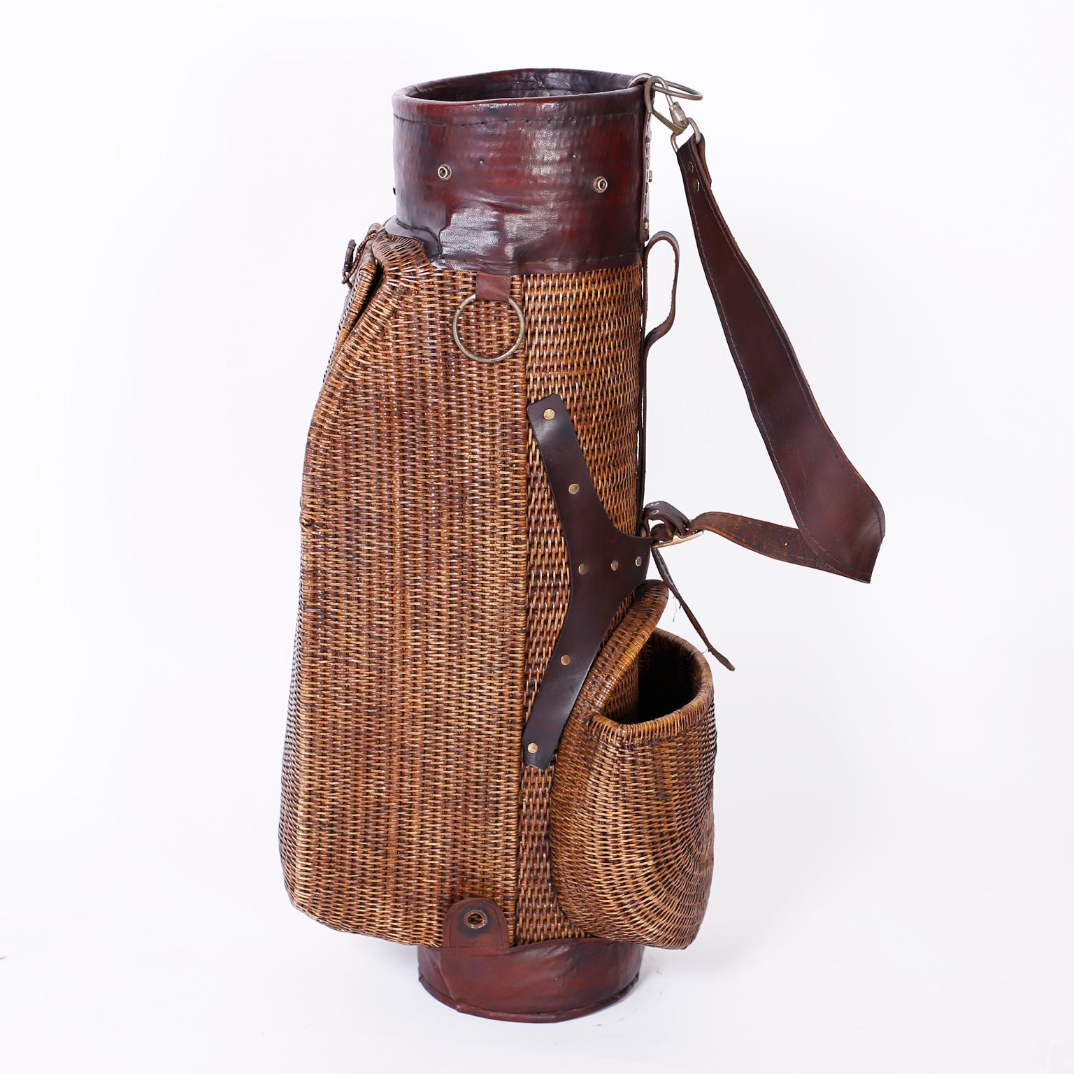 Anglo Indian British colonial style golf bag crafted with wicker over a wood frame with storage compartments and featuring brown leather straps, neck, and foot.