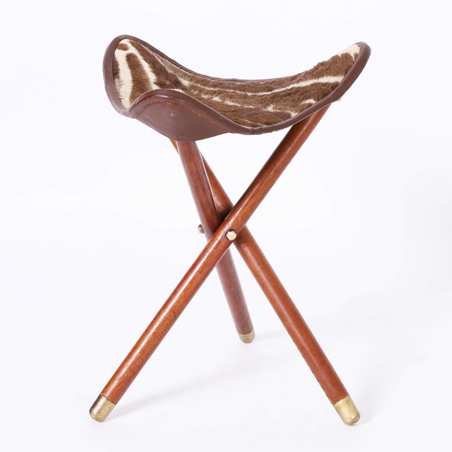 Midcentury British Colonial style folding zebra hide seat fitted to three mahogany legs with brass feet.