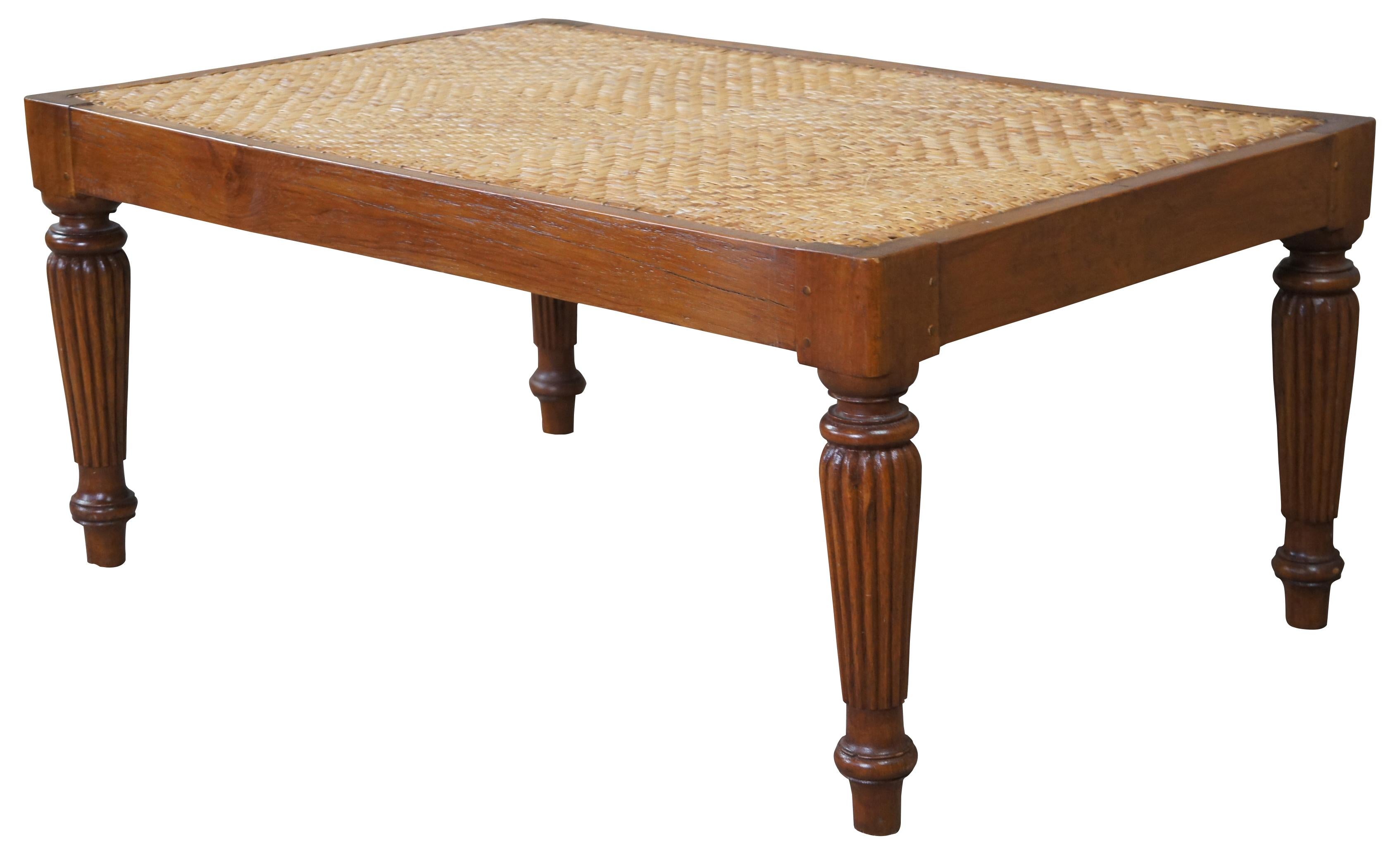British colonial style coffee table. Made during second half of the 20th century. Features a teak frame with woven rattan top. The table is supported by reeded legs leading to an arrow foot. Can be used as a bench.
   