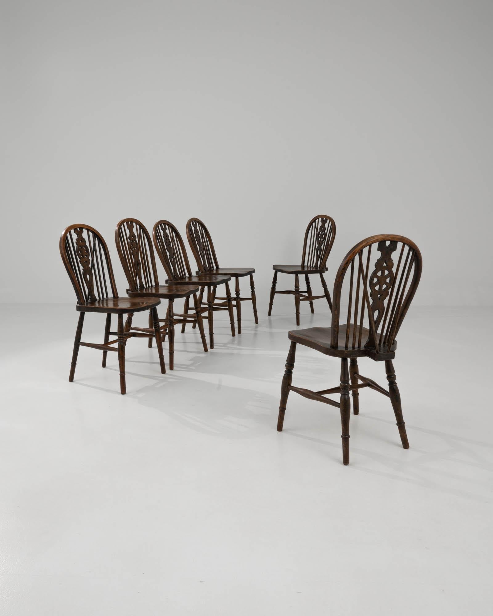 Combining a rich original patina with a handsome country silhouette, this set of six wooden dining chairs offer a timeless vintage accent. Made in the United Kingdom in the early 20th century, the form is typical for British farmhouse chairs.