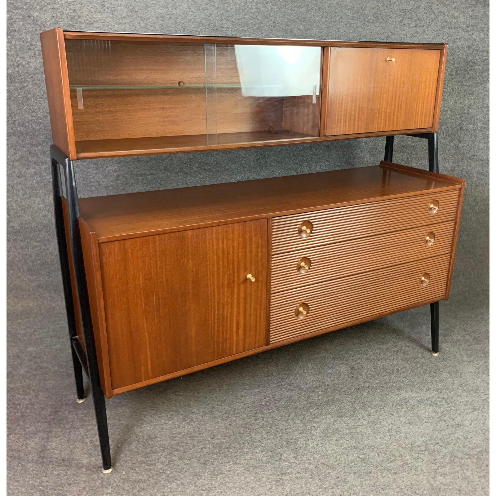 Here is a rare 1960s case piece in mahogany manufactured in England by Nathan in the 1960s.
This special hutch, recently imported from UK to California, features on its top a display cabinet with two glass sliding doors and a drop down door