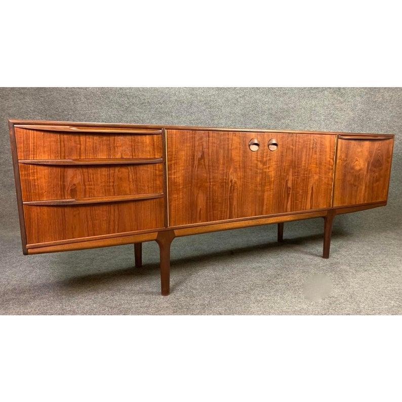 Here is another Classic example of a collectible long teak sideboard designed by Tom Robertson and manufactured by A. H. McIntosh in the 1960's before its recent importation to California. This organically designed credenza features beautiful