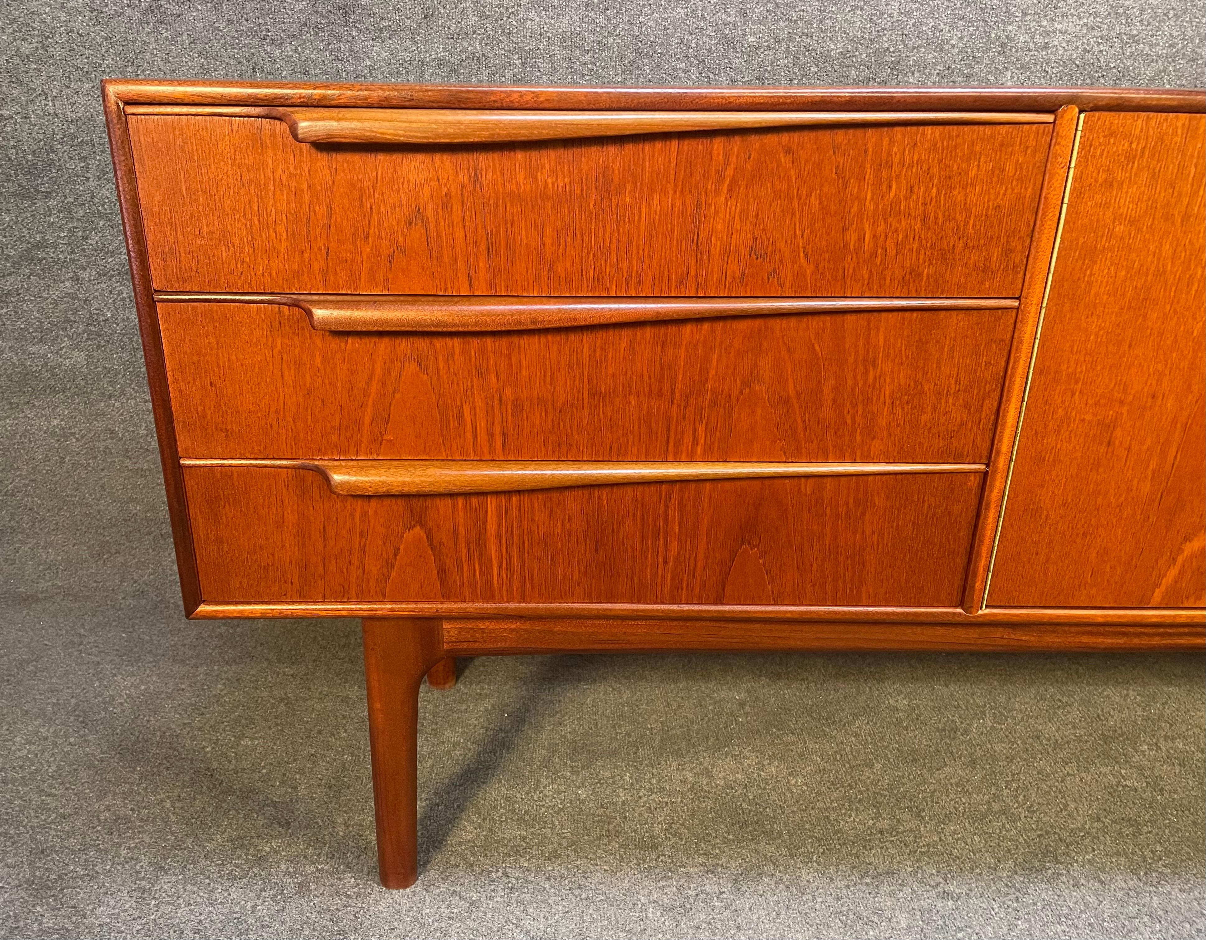 Here is a beautiful and rare British Mid-Century Modern sideboard manufactured in Scotland in the 1960s by A.H McIntosh Ltd.
This exquisite piece, recently imported from Europe tom California before its refinishing, features a vibrant wood grain, a