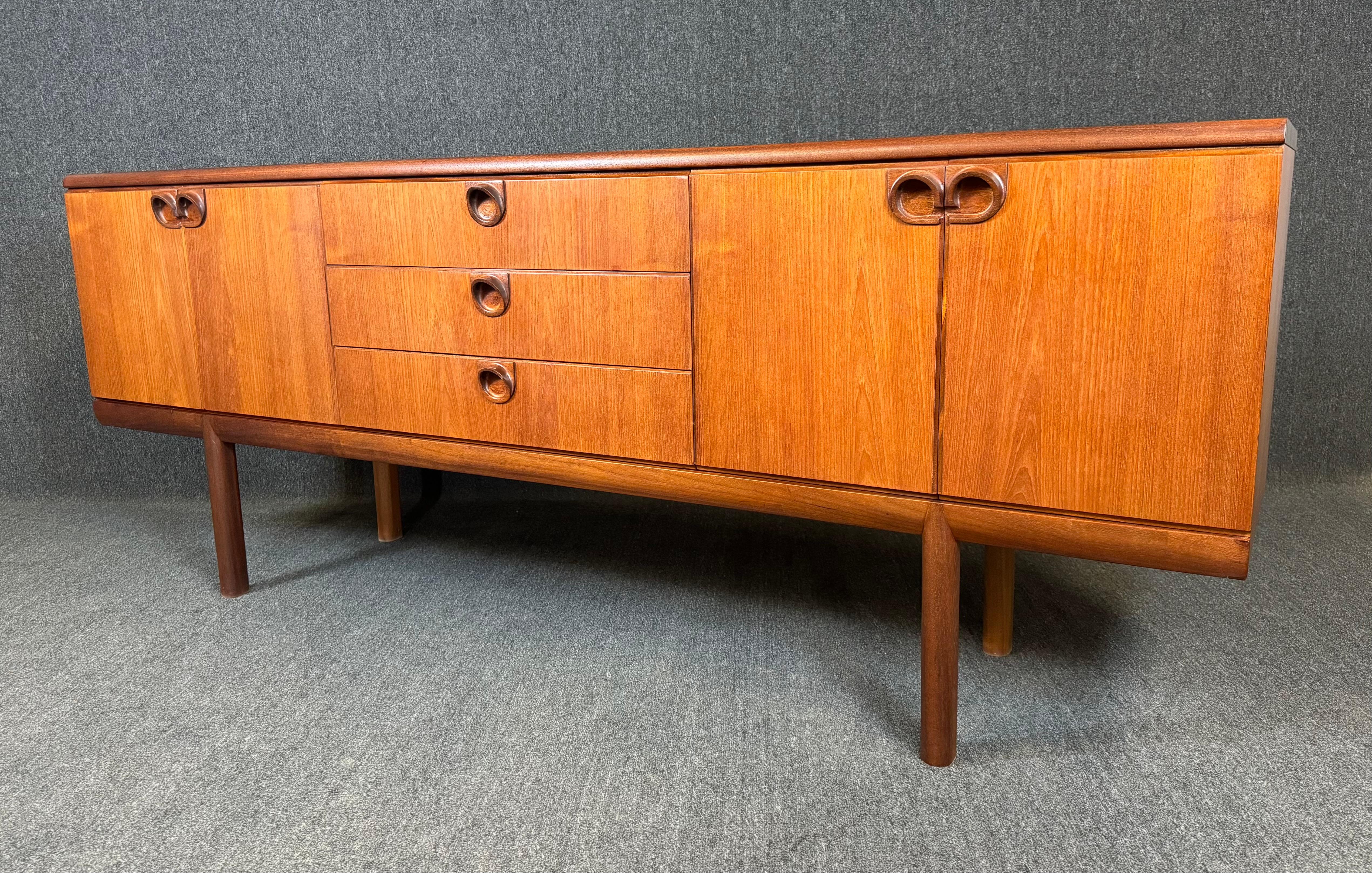 Here is a beautiful MCM sideboard in teak manufactured by McIntosh in Scotland in the 1960's. This sideboard, recently imported from England to California before its refinishing, features a vibrant wood grain, a central bank of three dove tail built