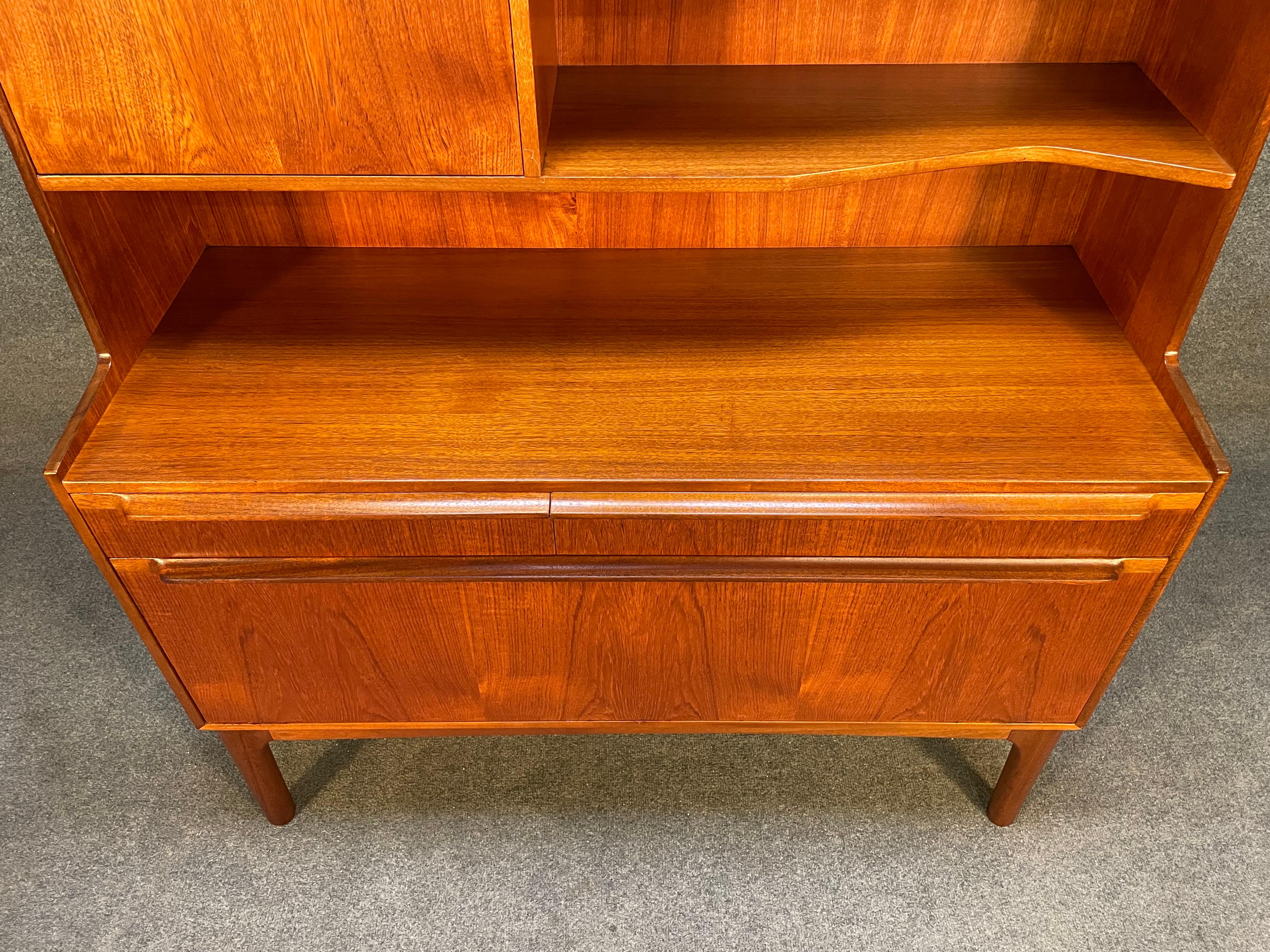 Here is a beautiful British Mid-Century Modern teak hutch-bookcase manufactured by A.H McIntosh Ltd in Scotland in the 1960s.
This exquisite piece, recently imported from Europe to California before its refinishing, features a vibrant wood grain