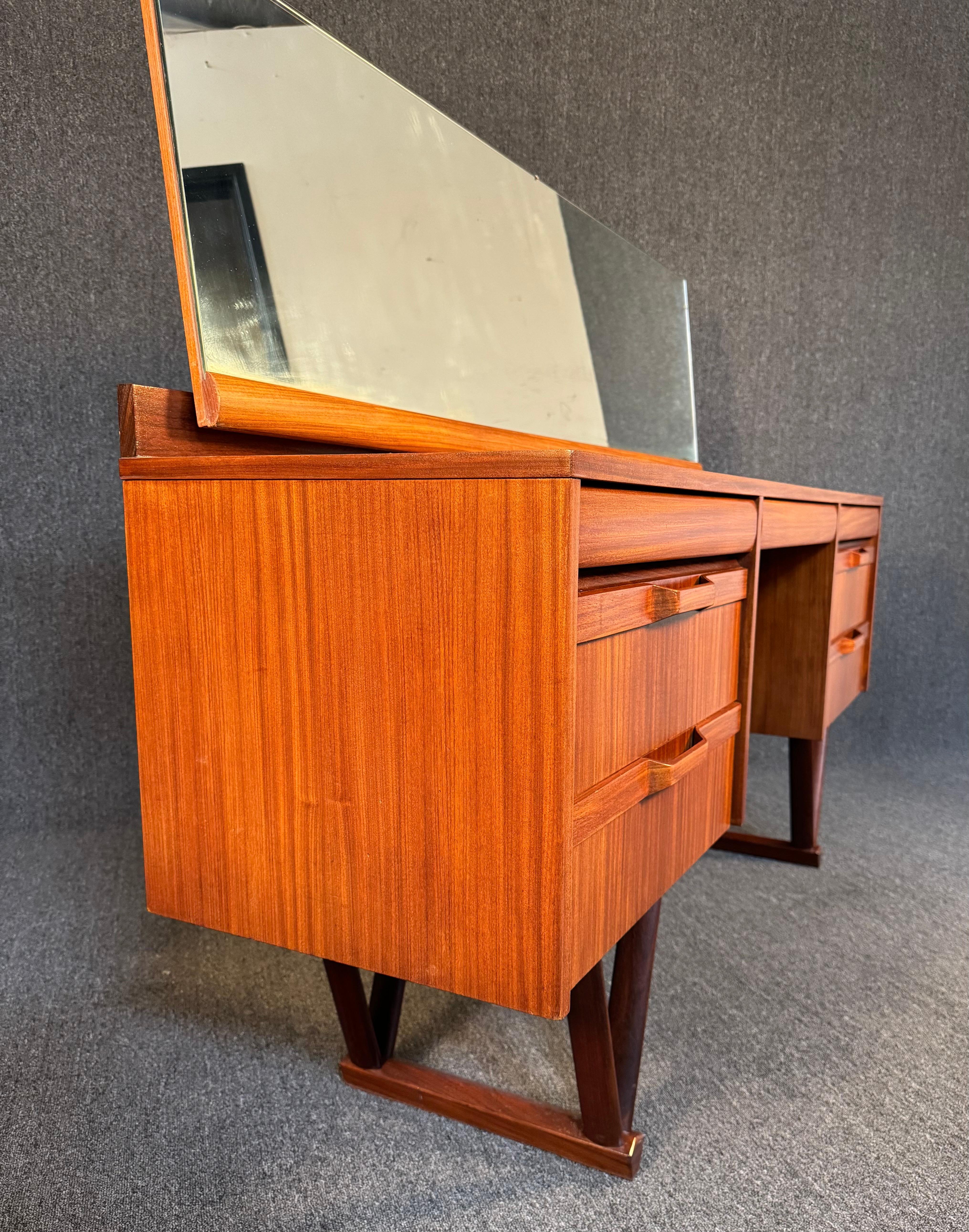 Here is a beautiful British MCM dressing table in afromasia teak manufactured by Elliotts of Newbury in England in the 1960's.
This special piece, recently imported from Europe to California before use refinishing, features a vibrant wood grain, a